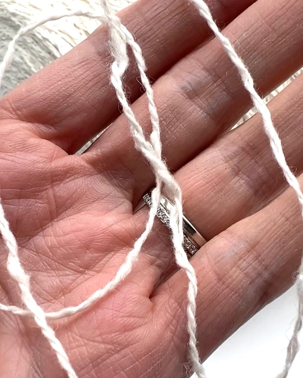 Close-up of a hand holding white yarn