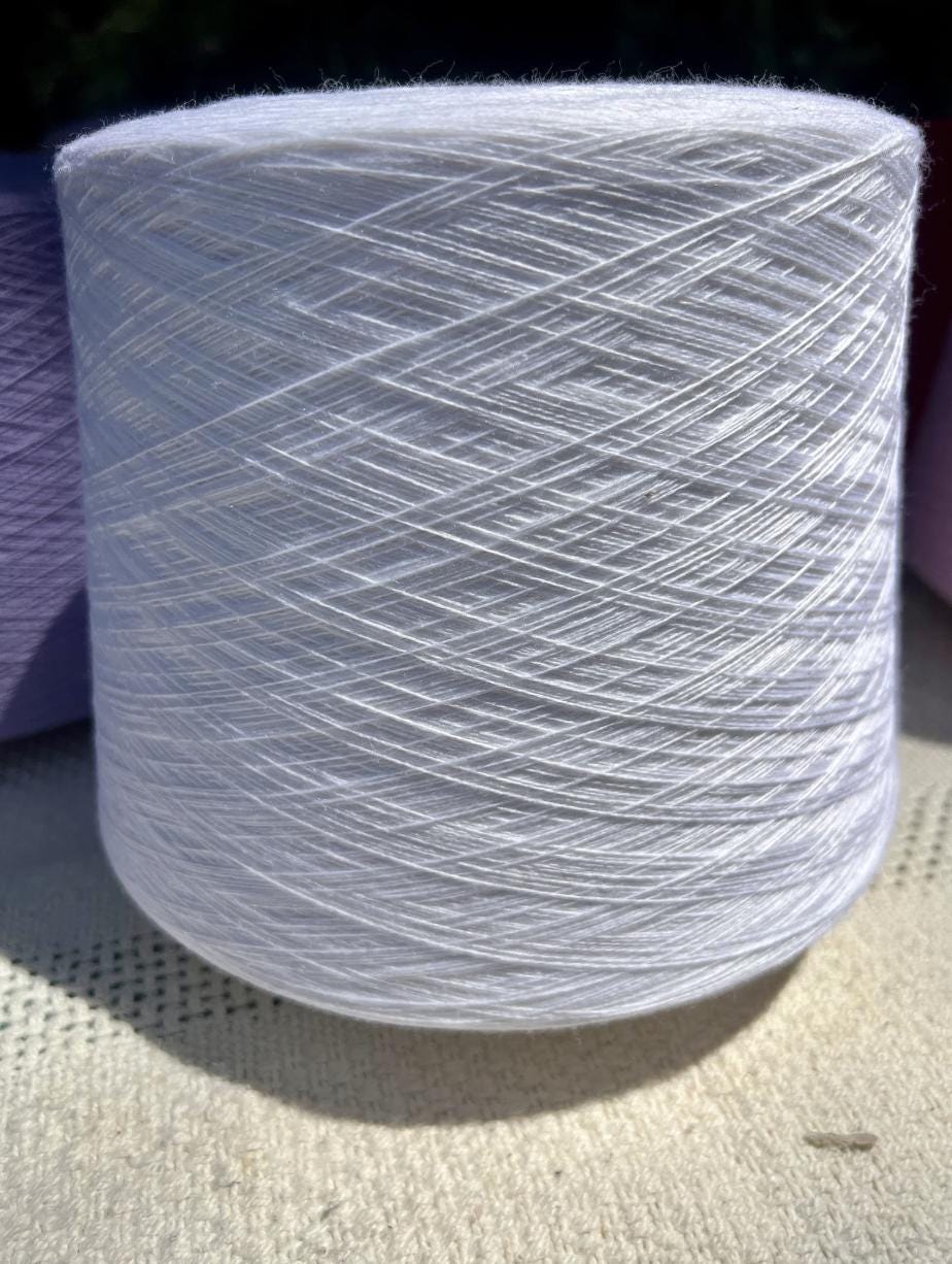Spool of white yarn on a textured surface