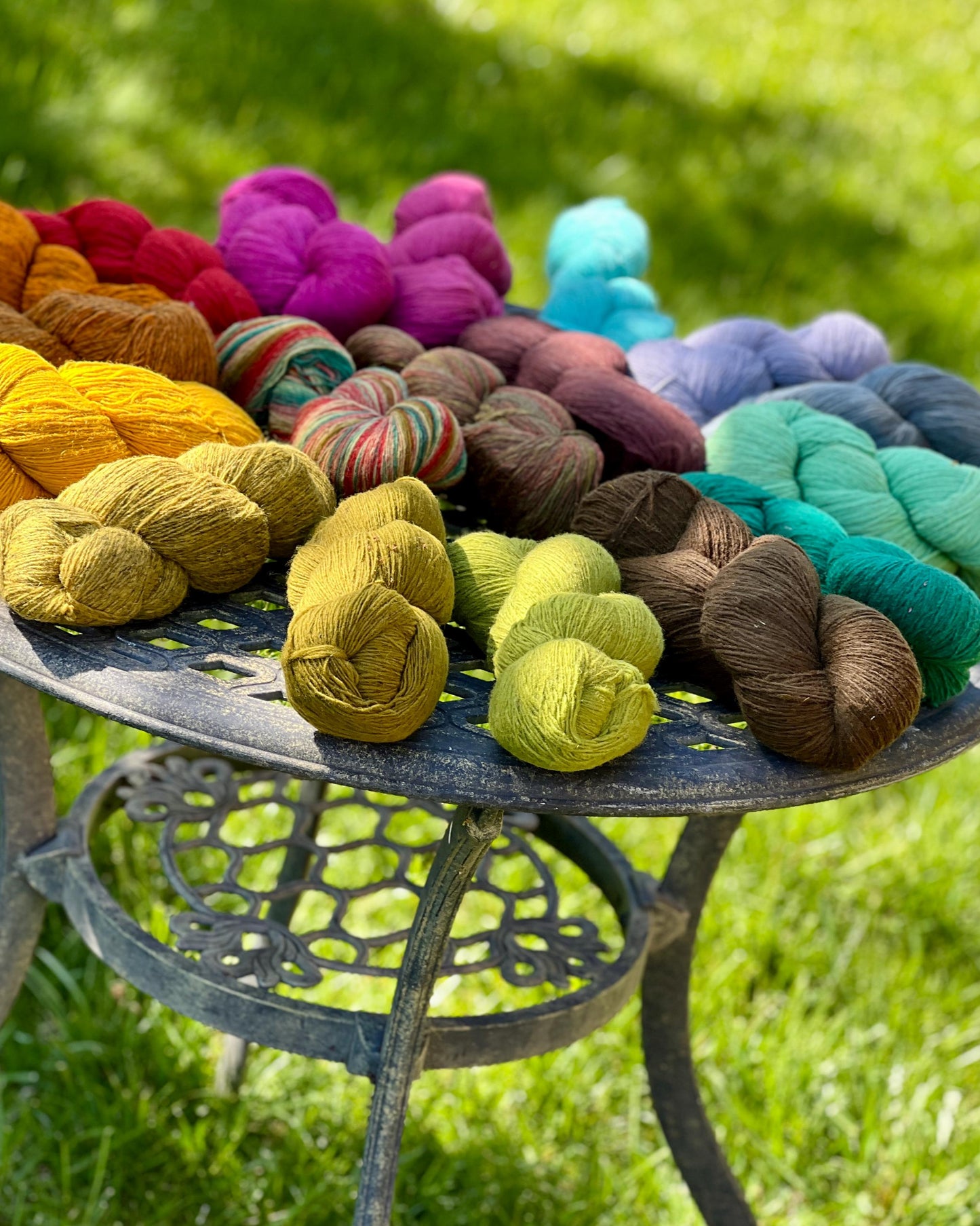 Assorted colorful yarn skeins on a metal table outdoors.