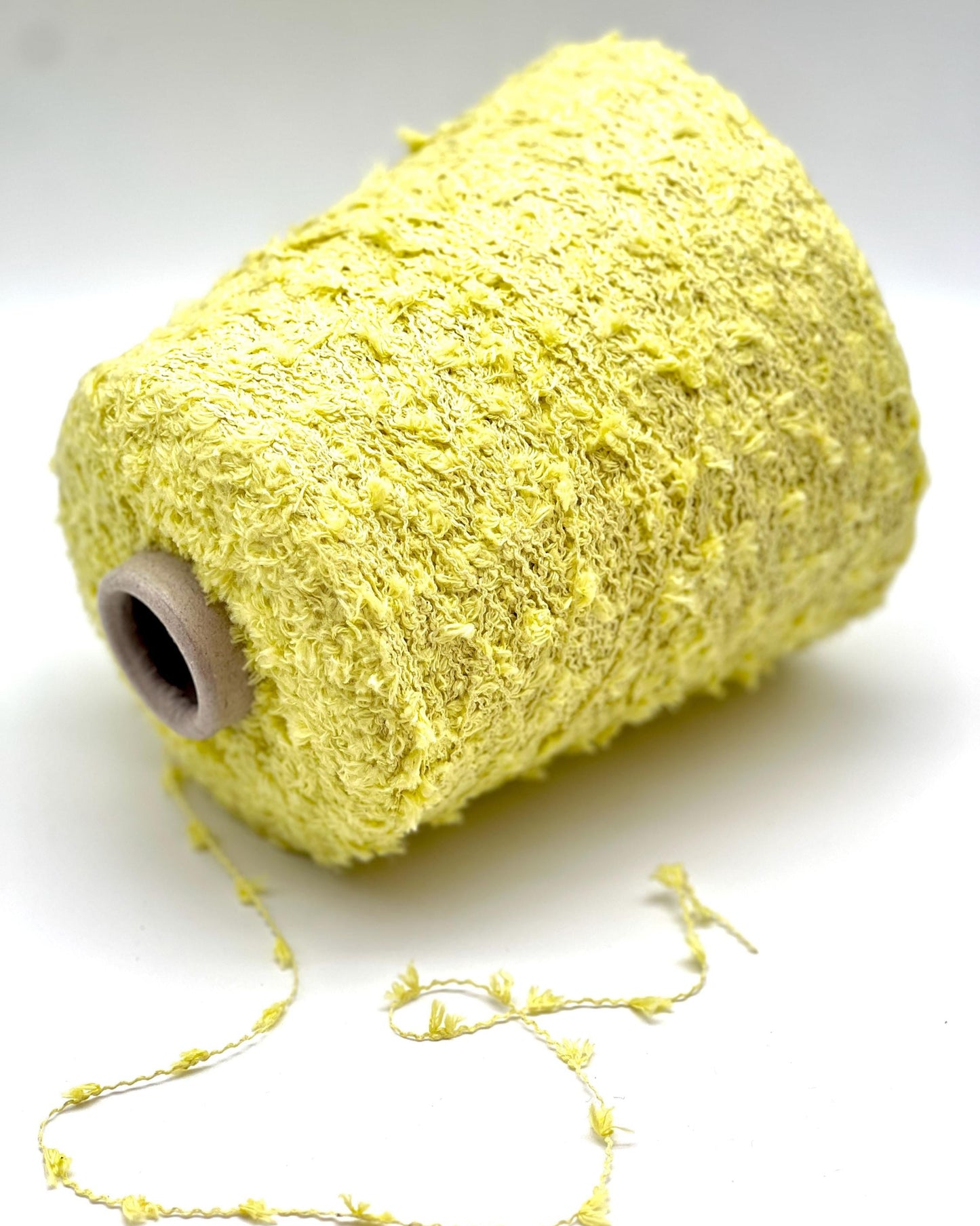 Spool of yellow yarn on a white background