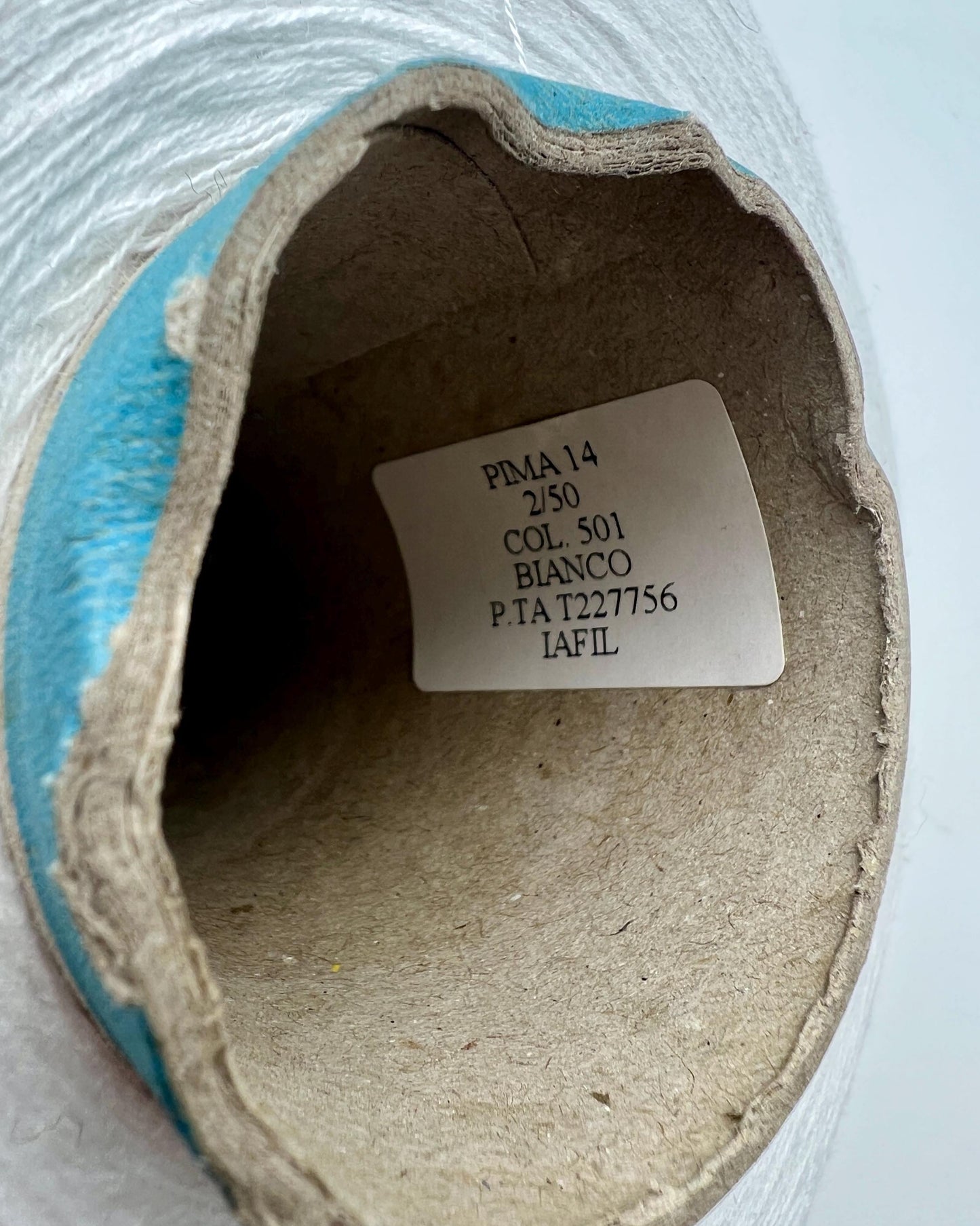 Close-up of a roll of paper with a label inside, on a light gray background.