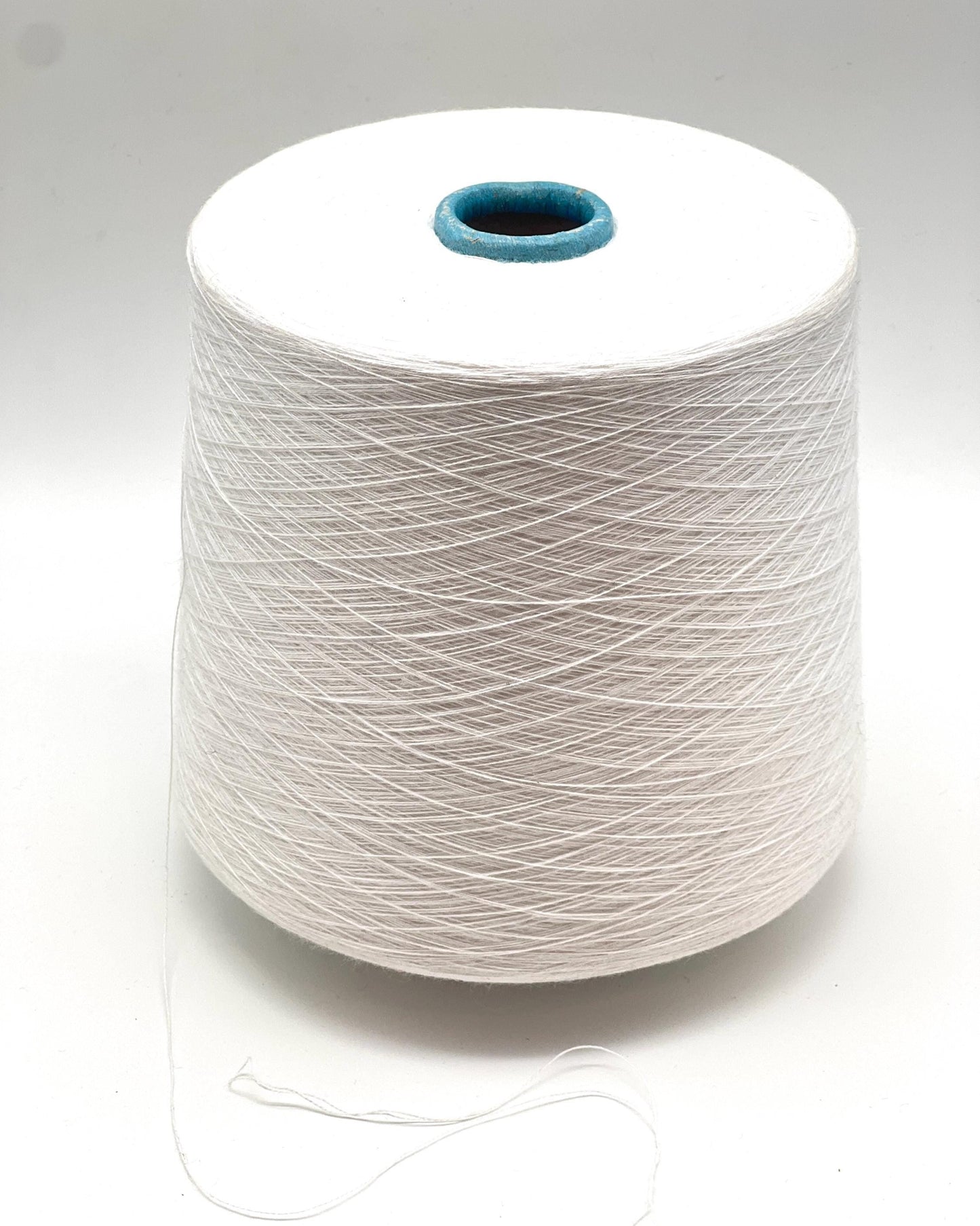 Spool of white yarn on a gray background