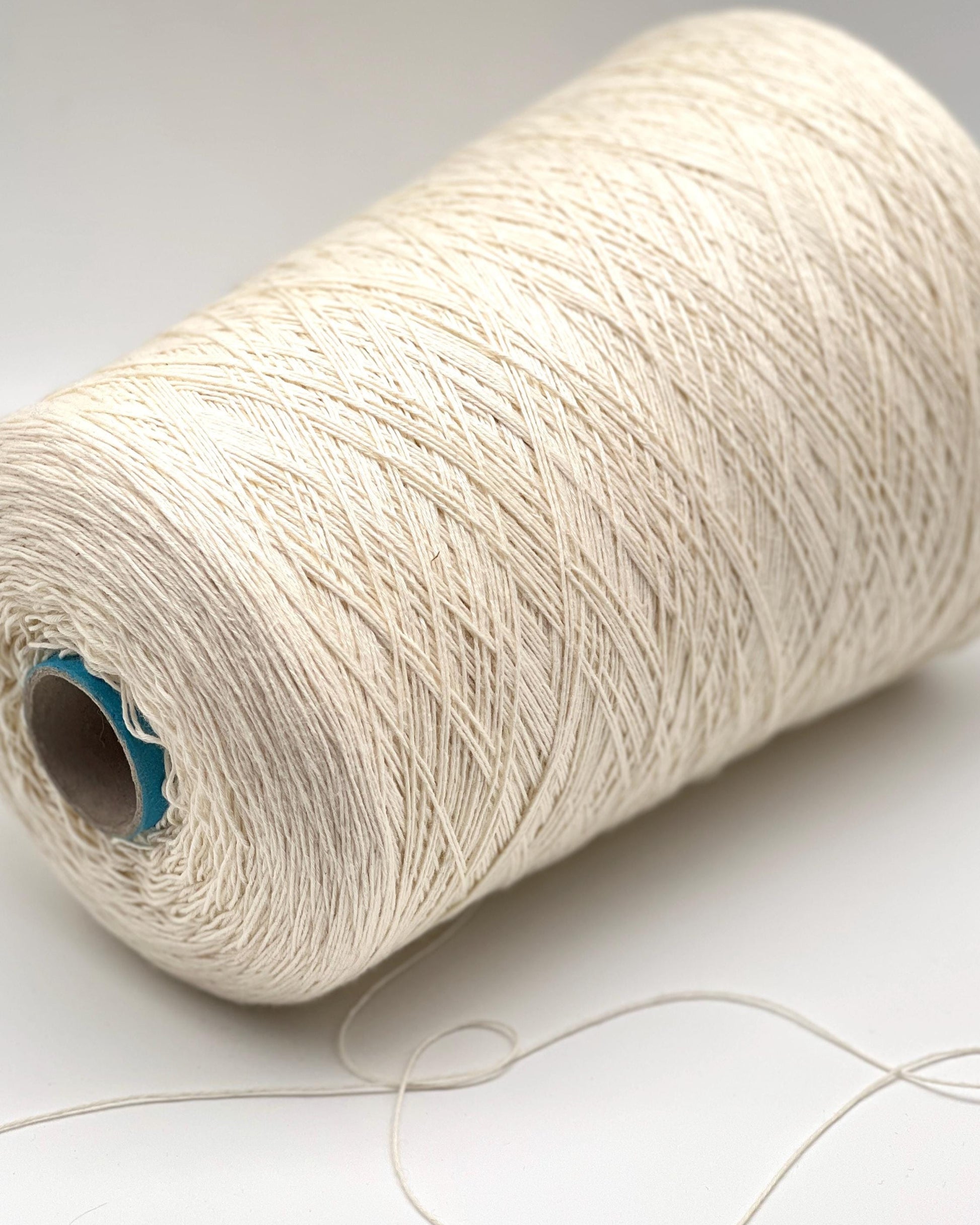 Spool of beige yarn on a white background