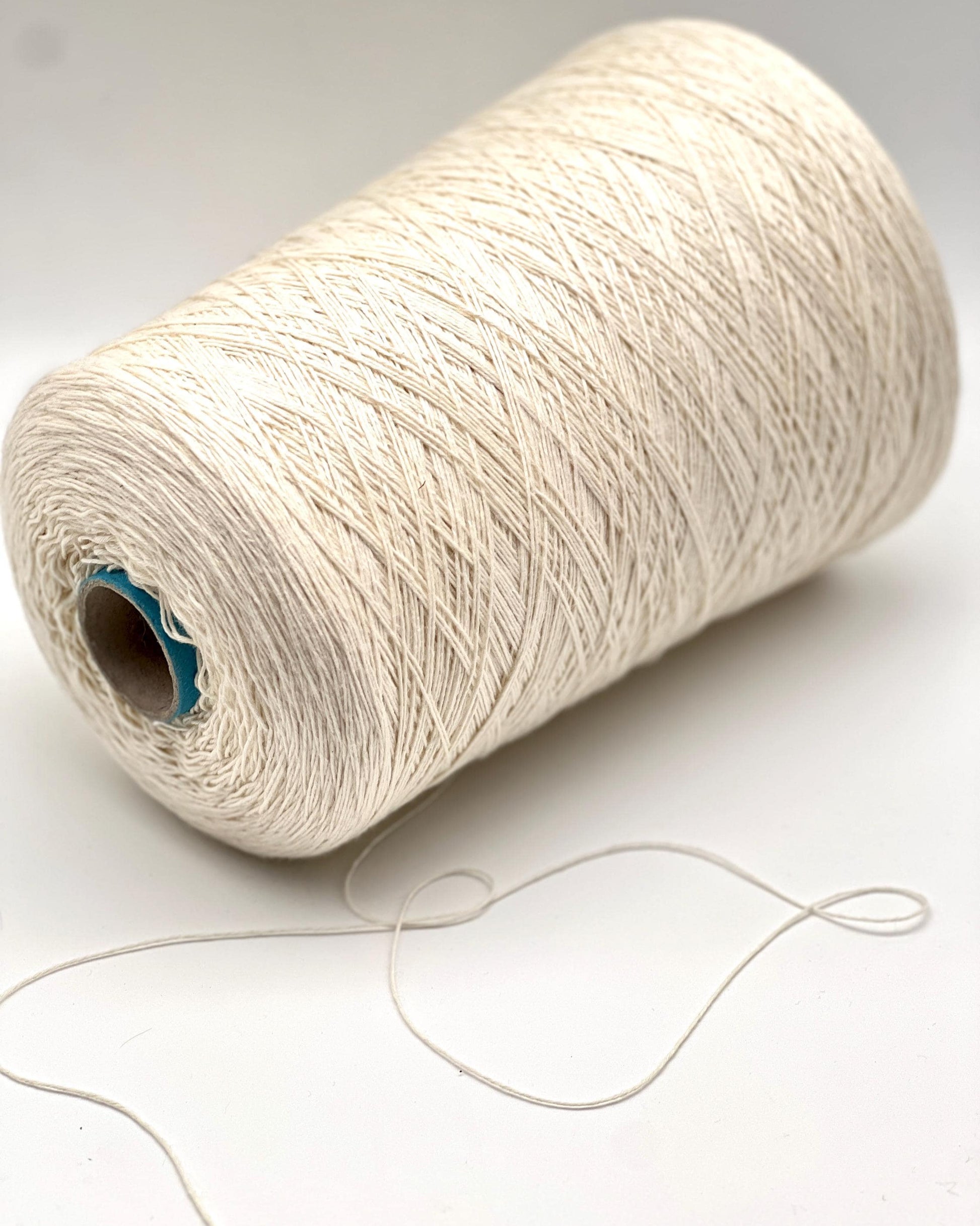 Spool of white yarn on a light gray background