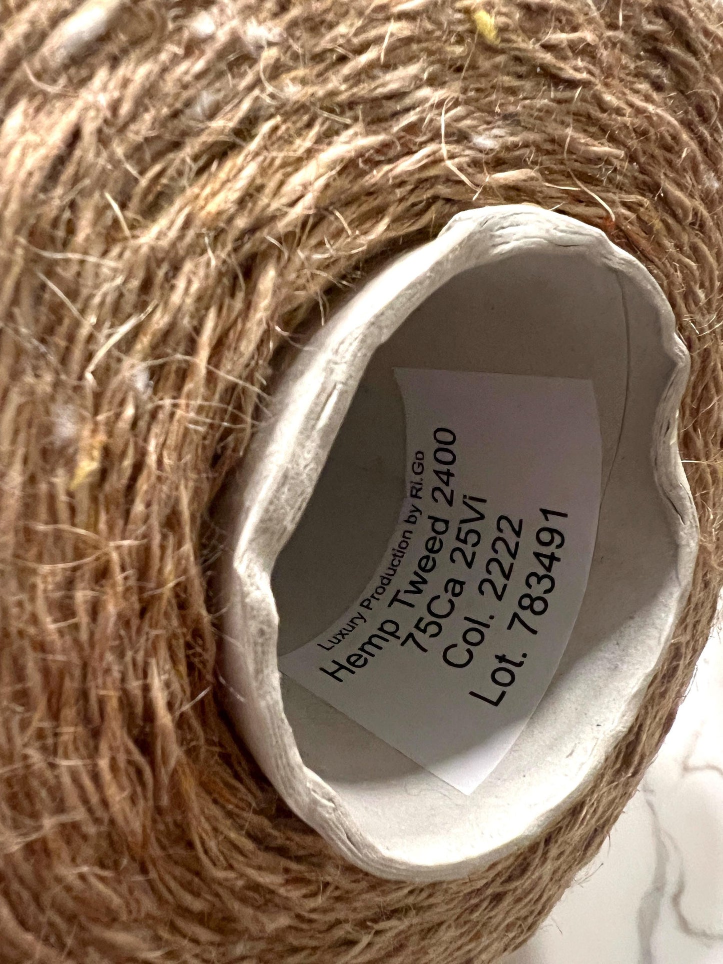 Close-up of a roll of hemp twine with a label on a marble surface