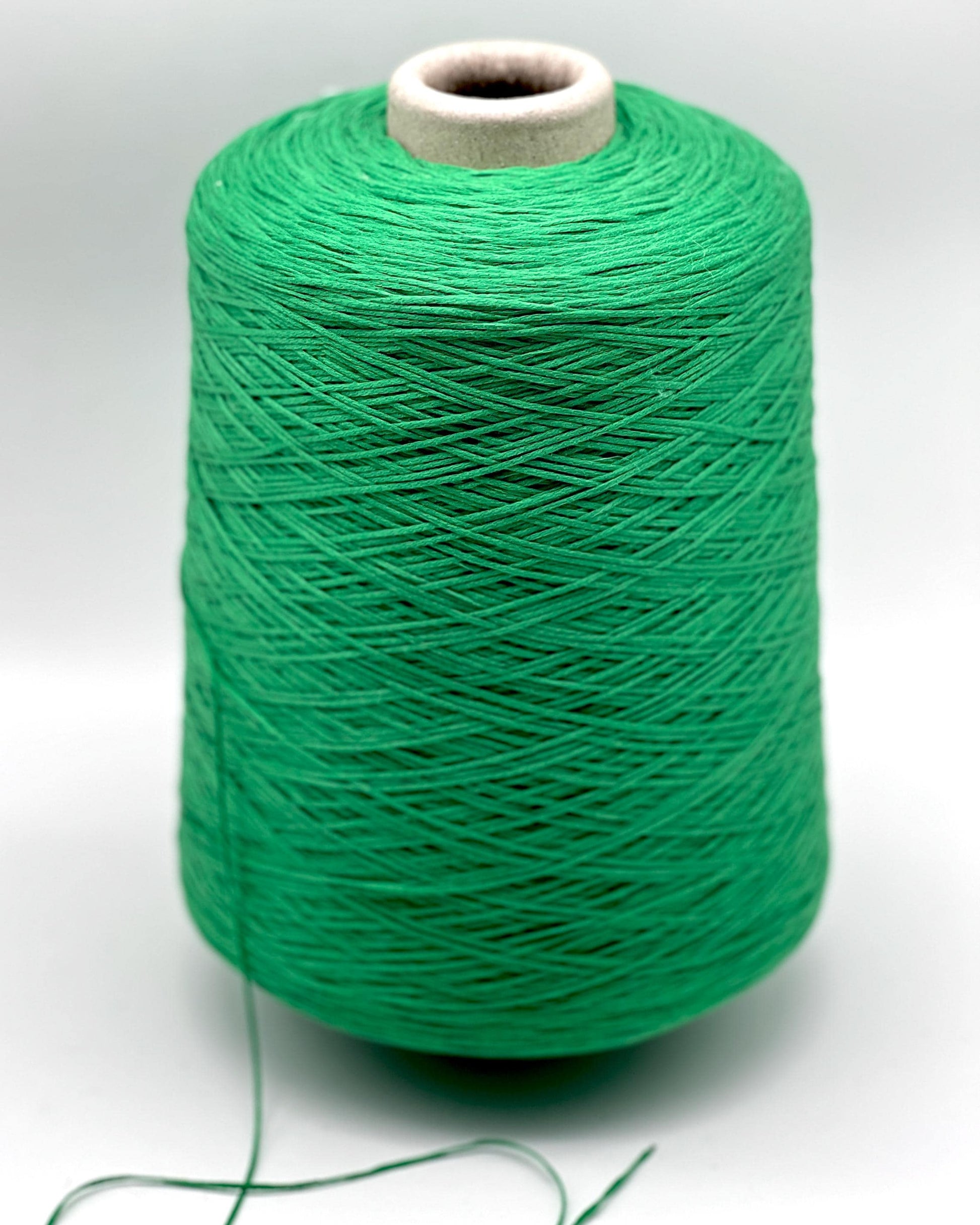 Spool of green thread on a white background