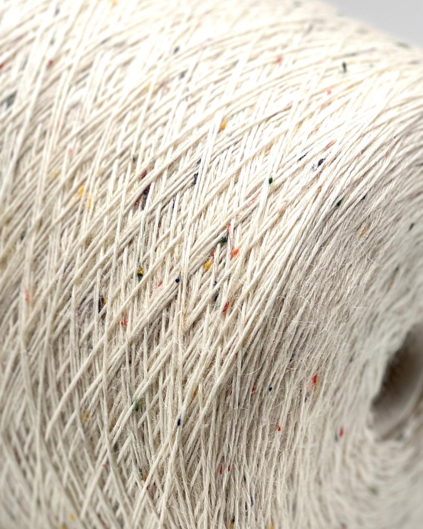 Close-up of a roll of beige yarn with specks of other colors.