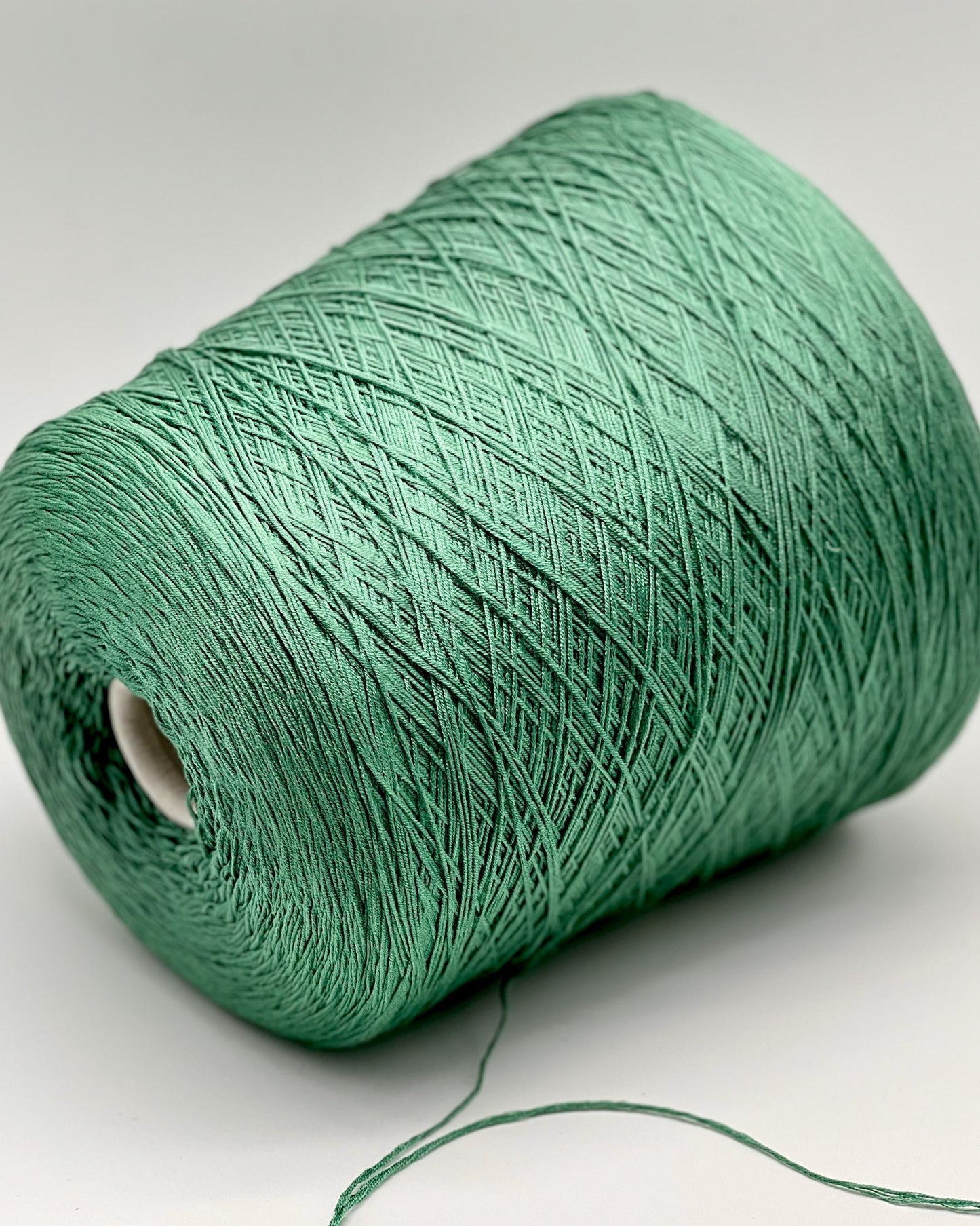 Green spool of yarn on a white background