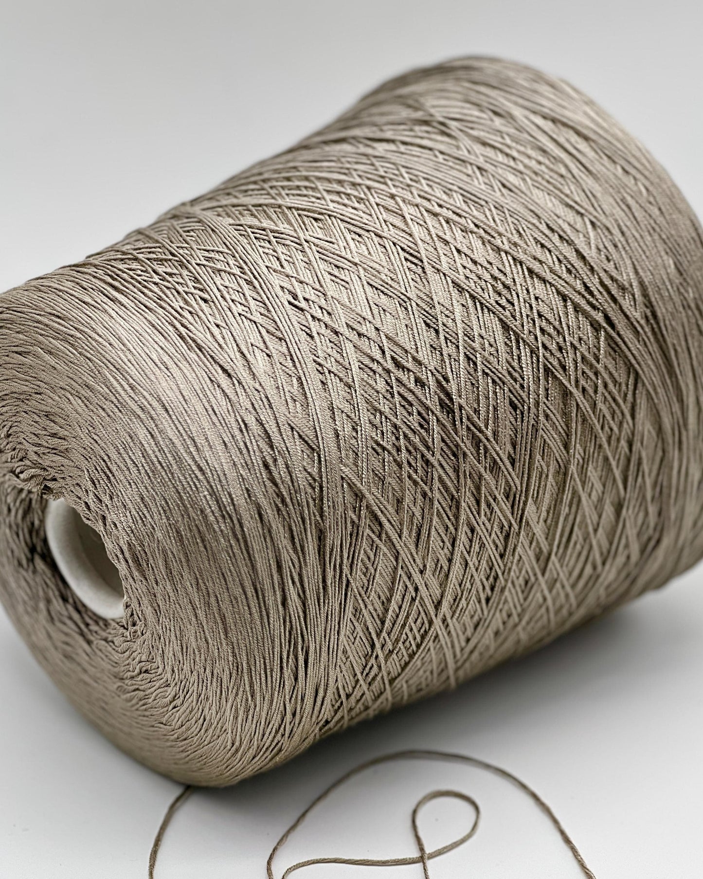Close-up of a roll of beige thread on a white background