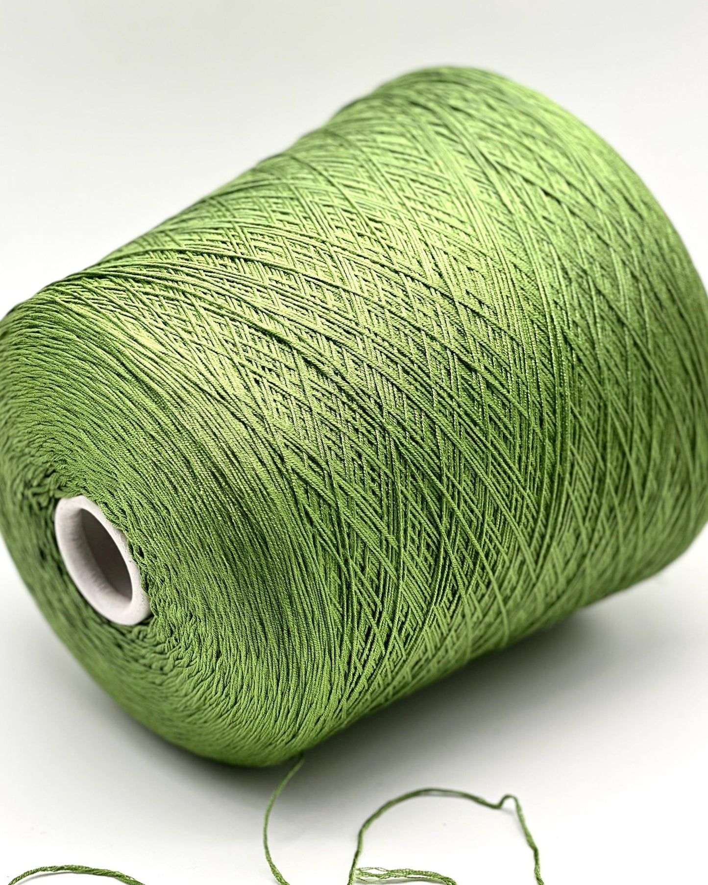 Green spool of yarn on a white background