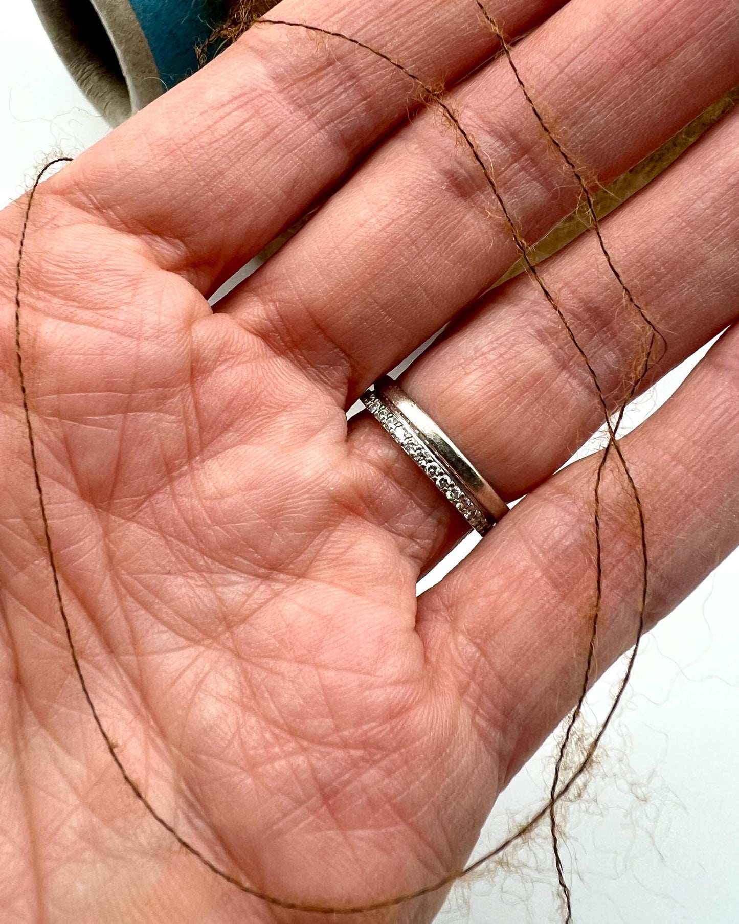 Close-up of a hand wearing a silver ring with a blurred background