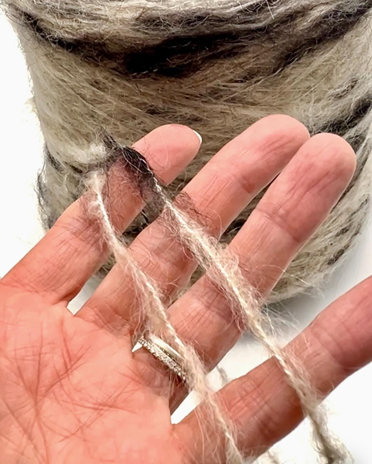 Hand holding a strand of natural fiber against a blurred background