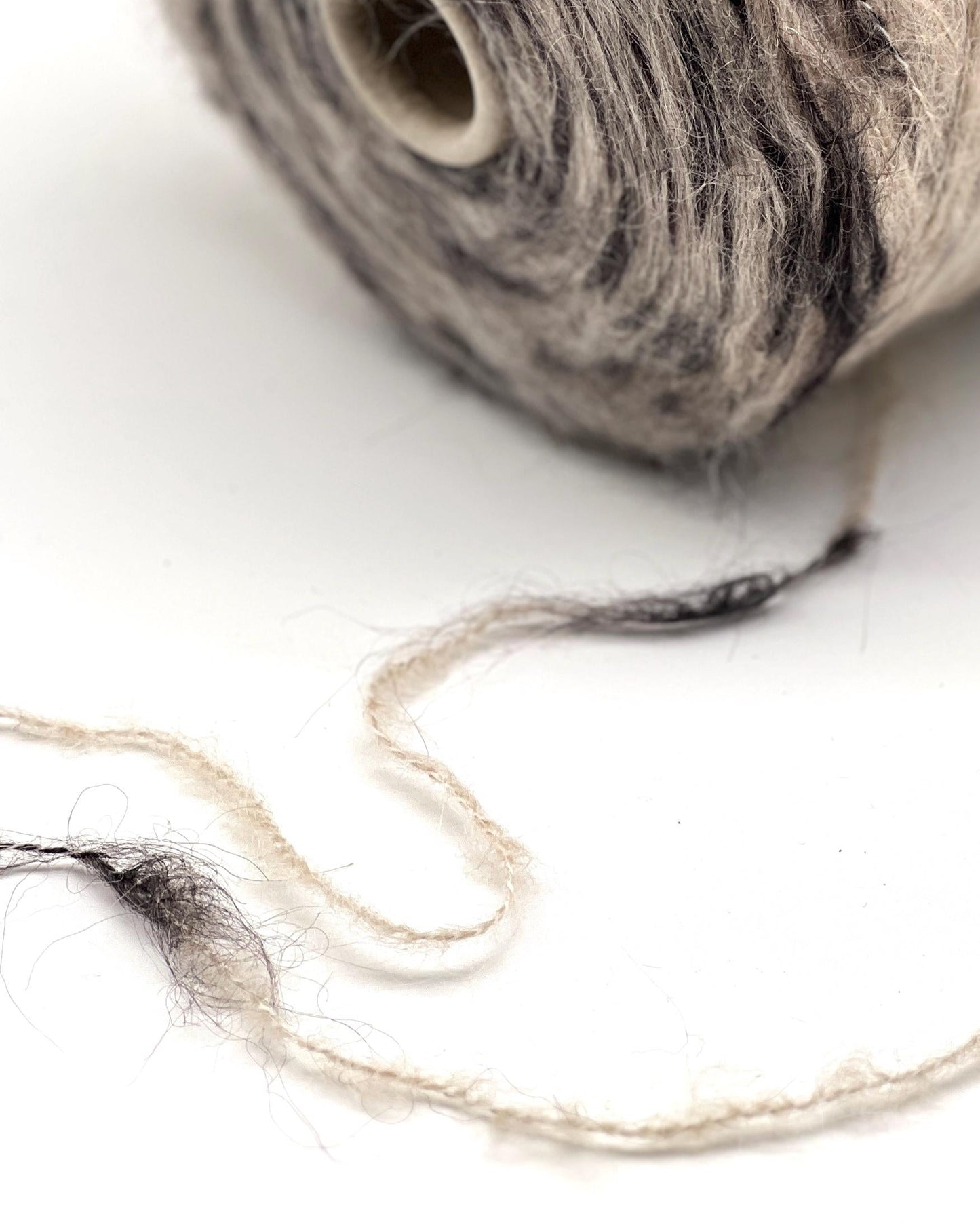 Ball of gray yarn with a few strands on a white background