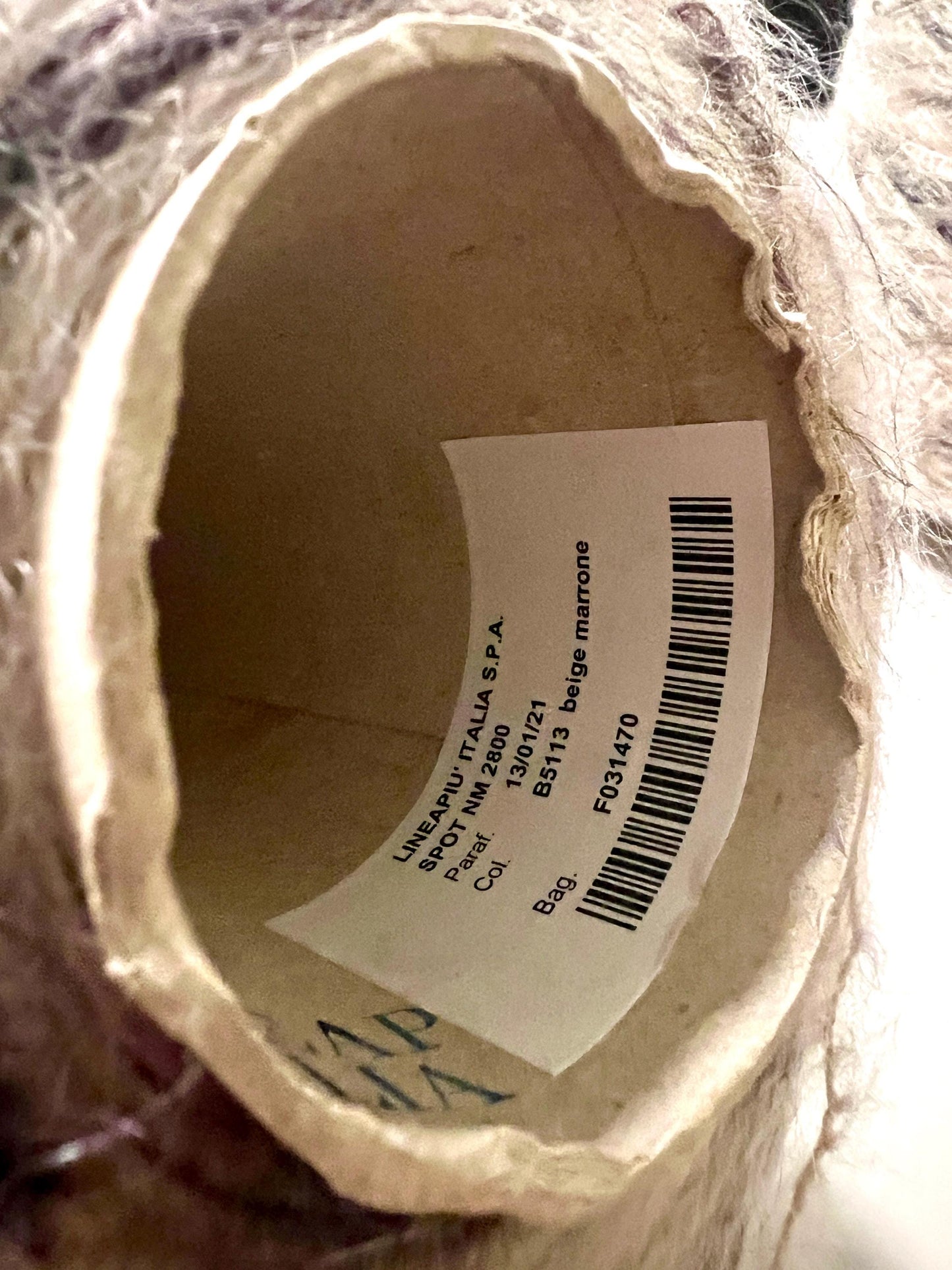 Close-up of a label inside a yarn ball with text and a barcode.