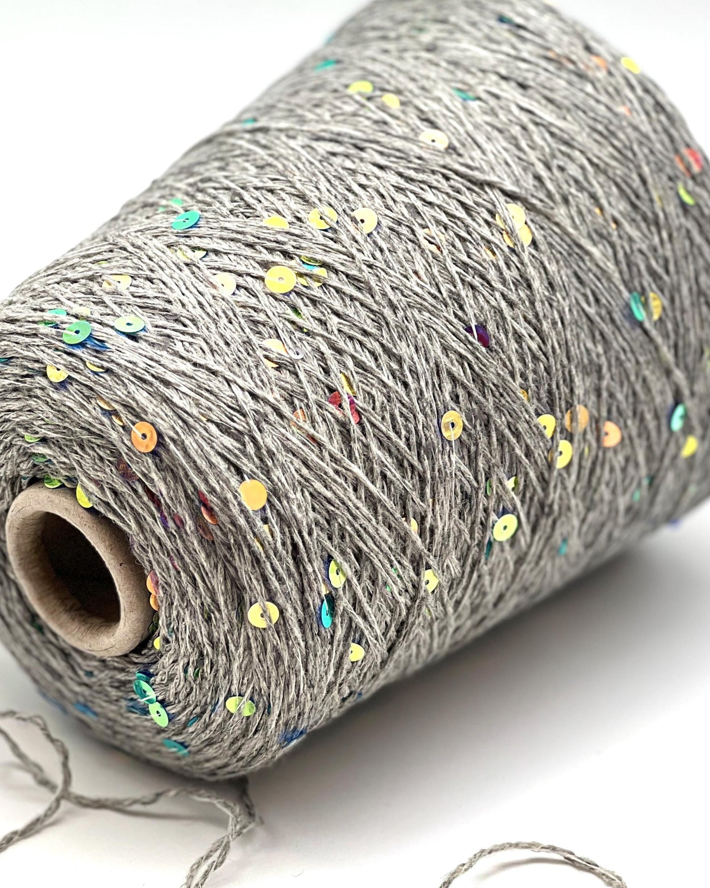 Roll of gray yarn with colorful specks on a white background