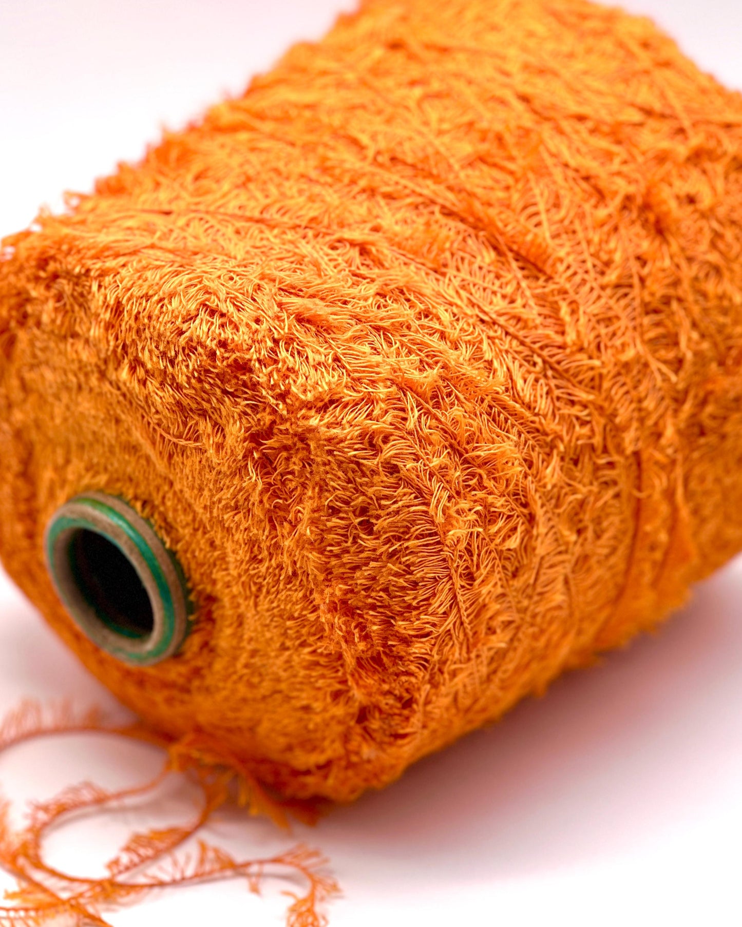 Close-up of a roll of orange yarn on a white background