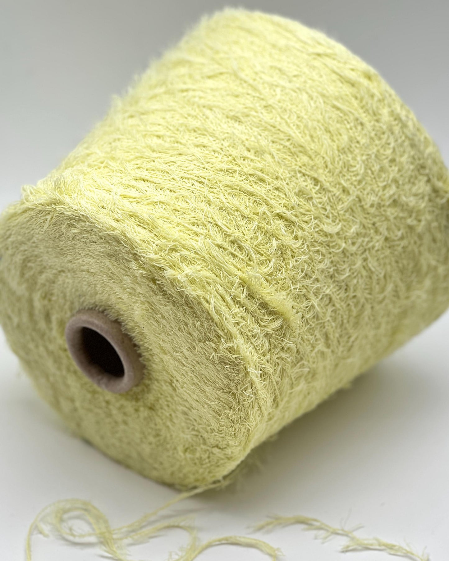 Spool of light green yarn on a white background