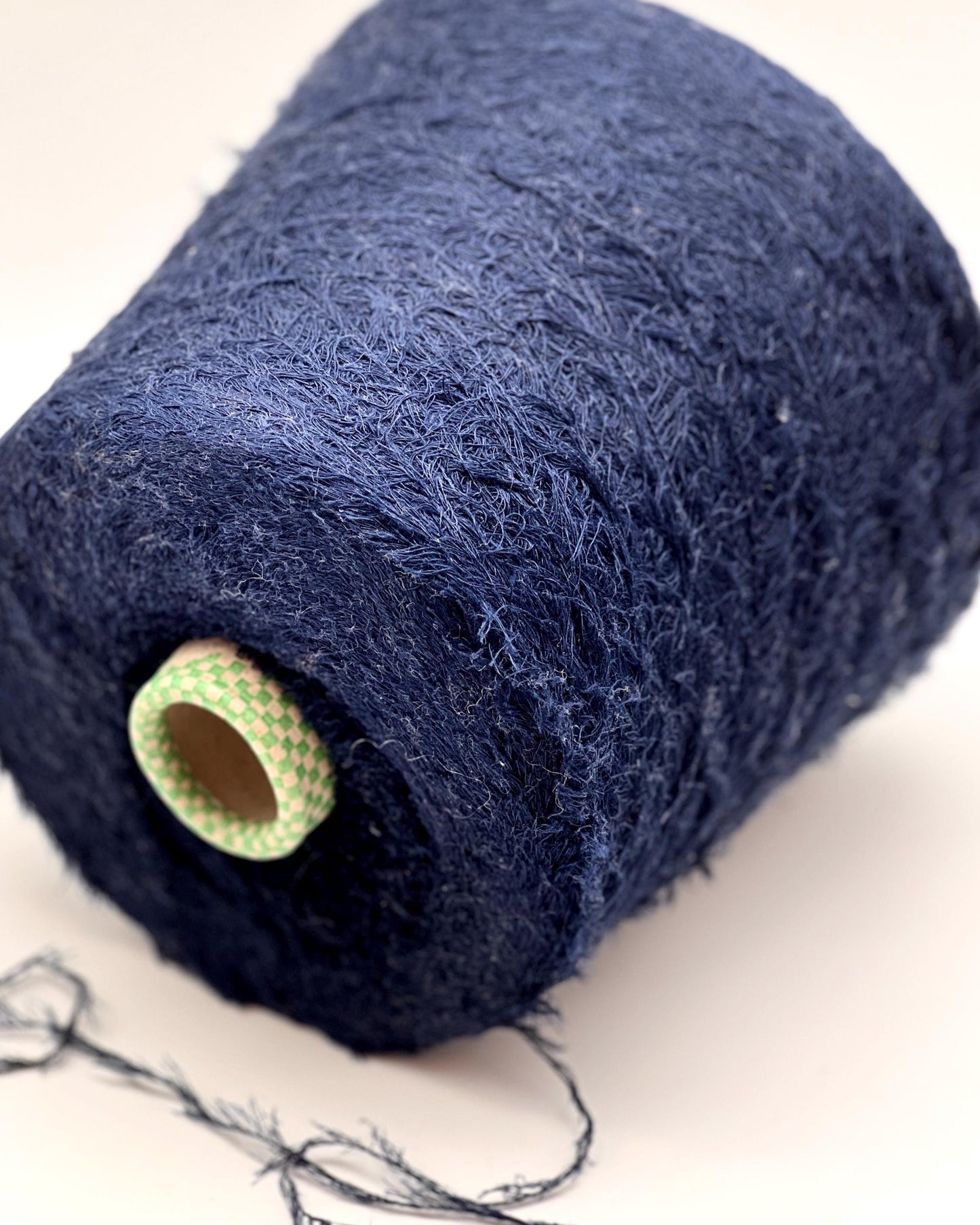 Spool of dark blue yarn on a light background