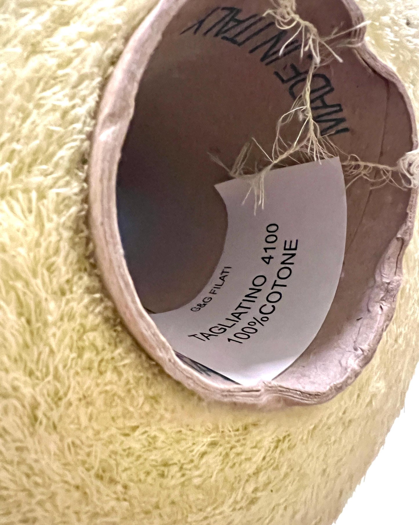 Close-up of a spool of yellow thread with a label on a white background