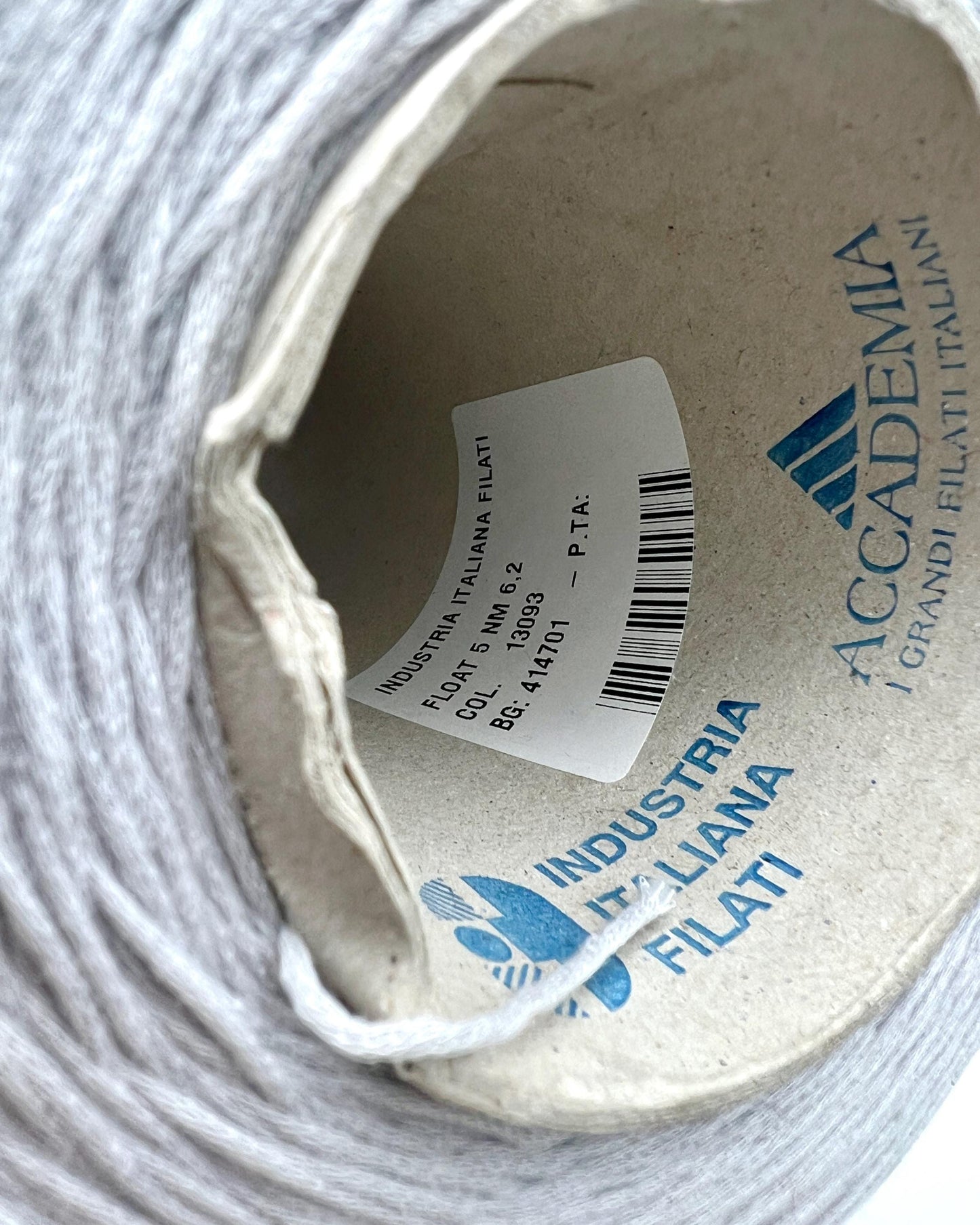 Close-up of a spool of yarn with 'Accademia Industria Italiana Filati' branding.