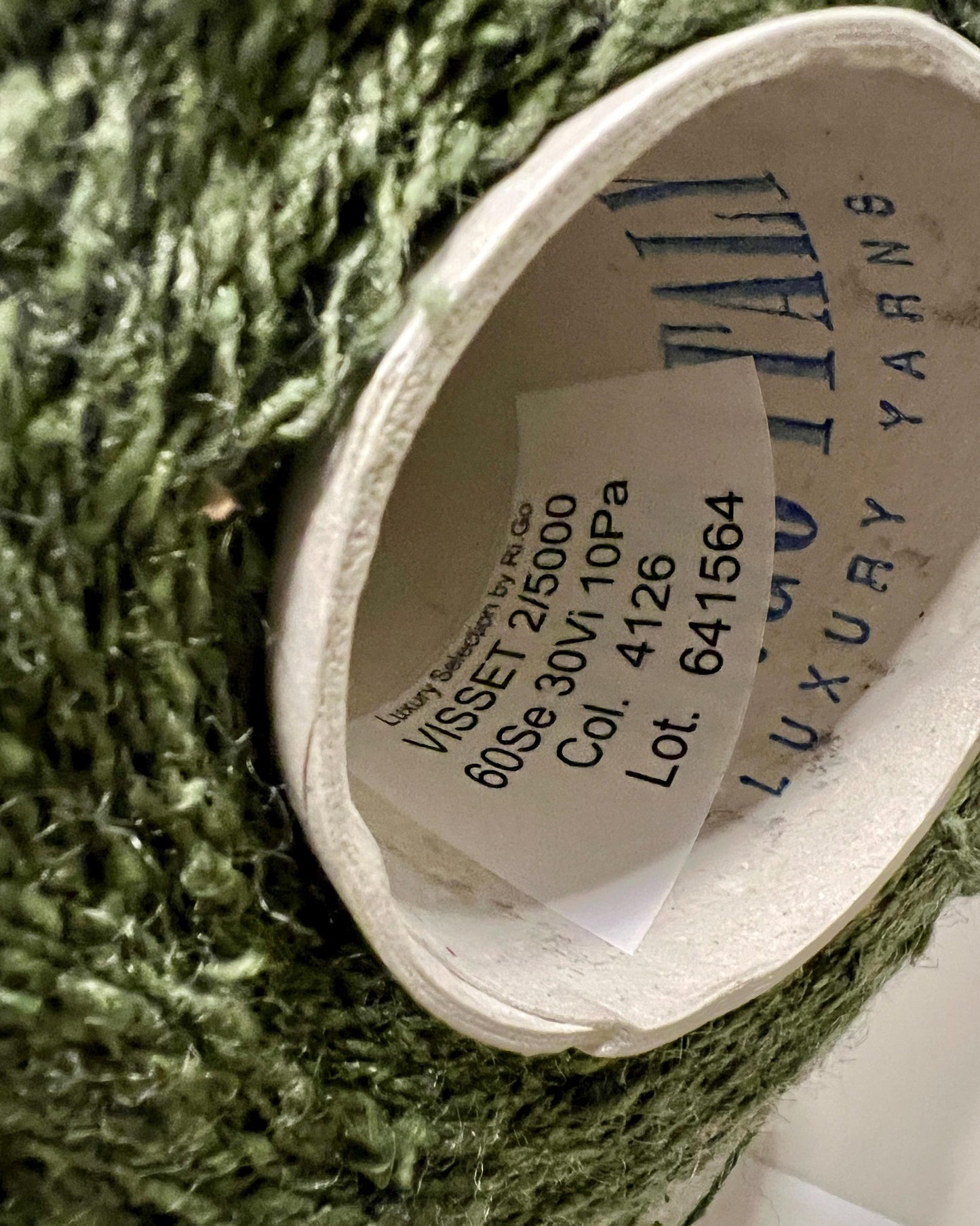 Close-up of a green yarn ball with a label on a textured surface