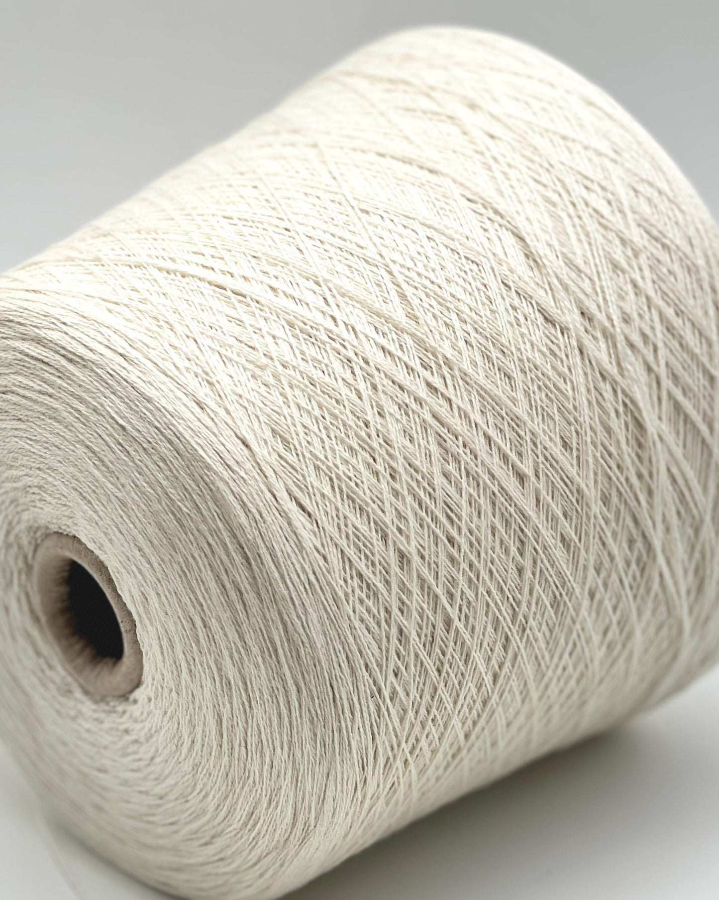 Spool of white yarn on a gray background