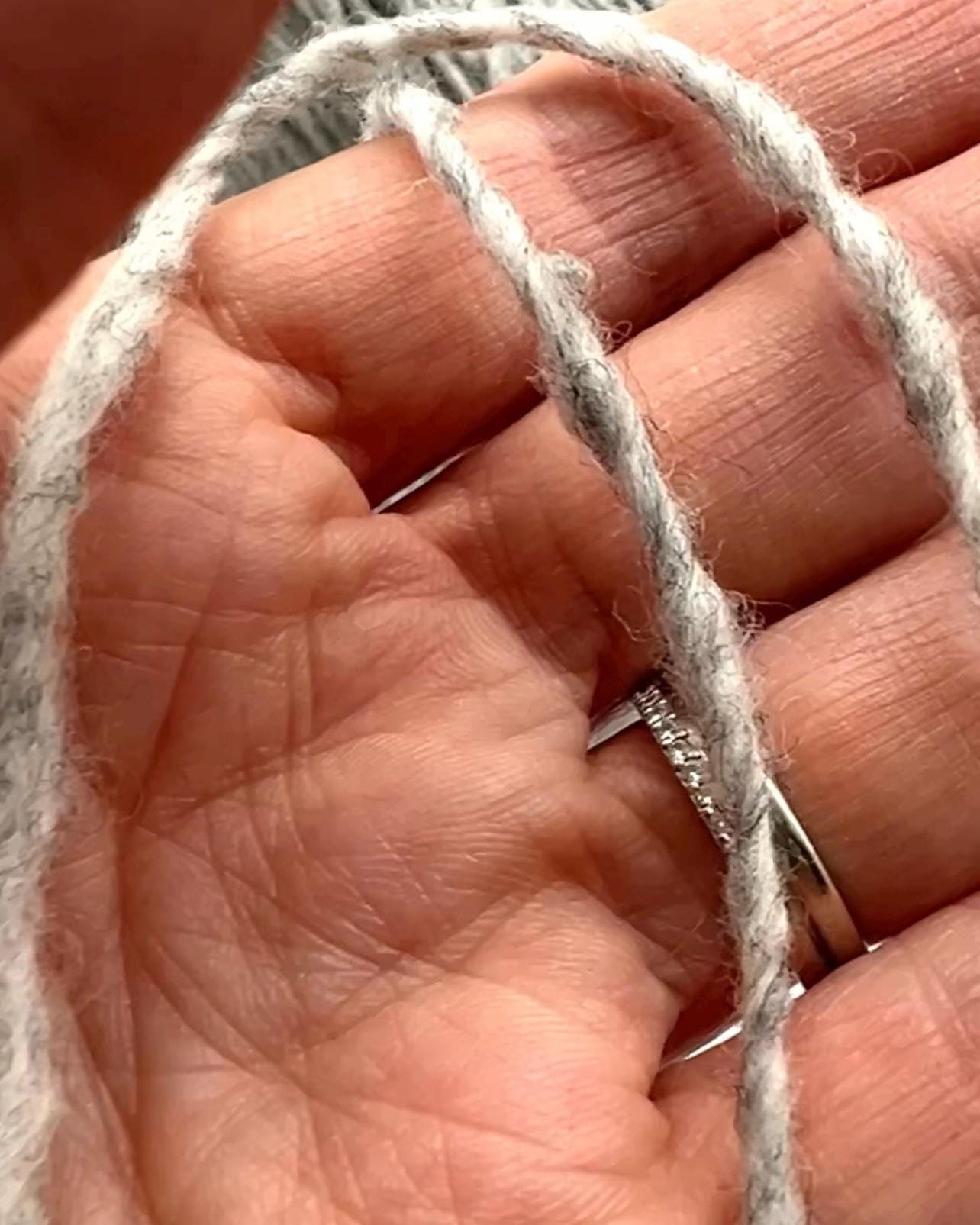 Close-up of hands holding a piece of white yarn.