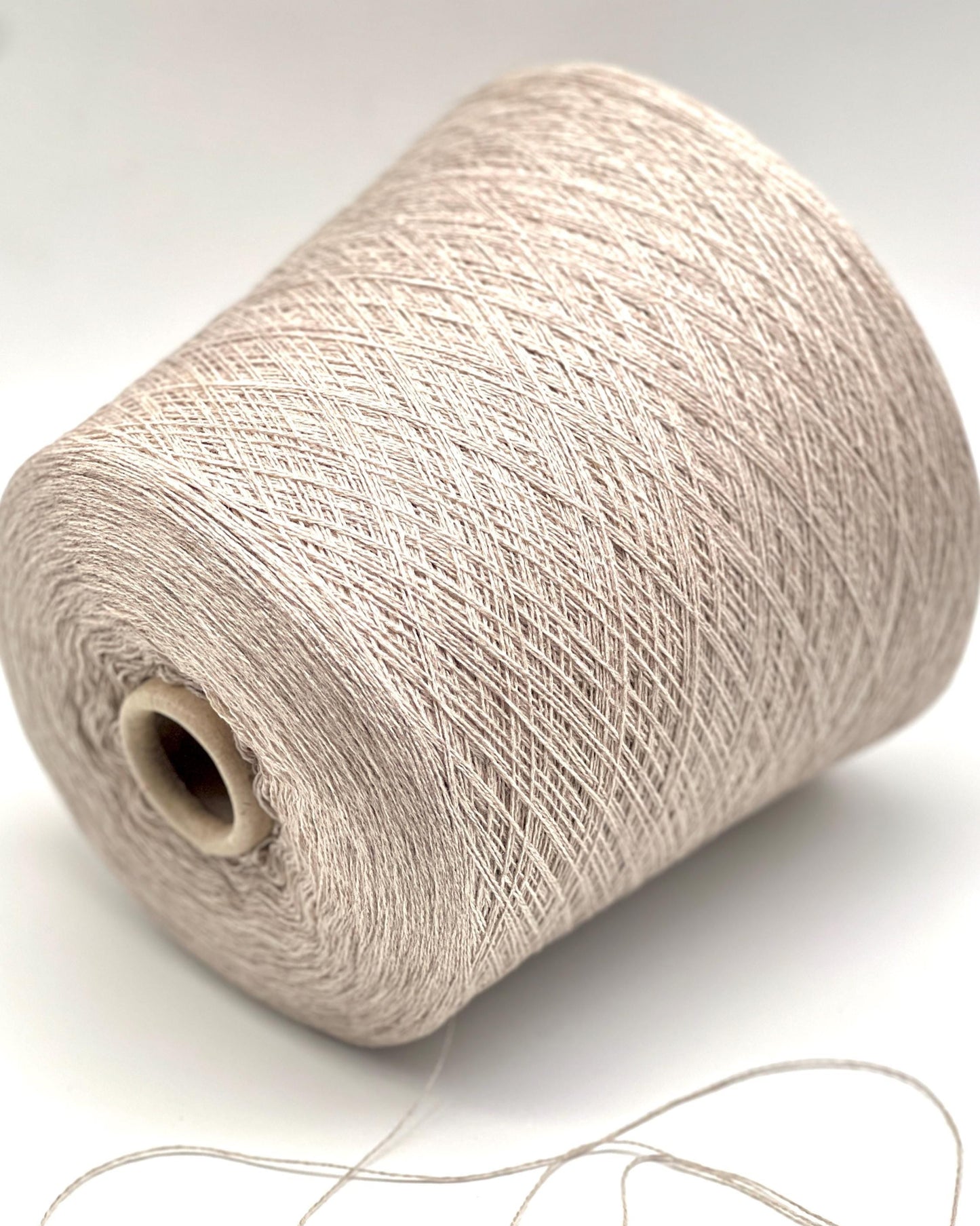 Spool of beige yarn on a white background