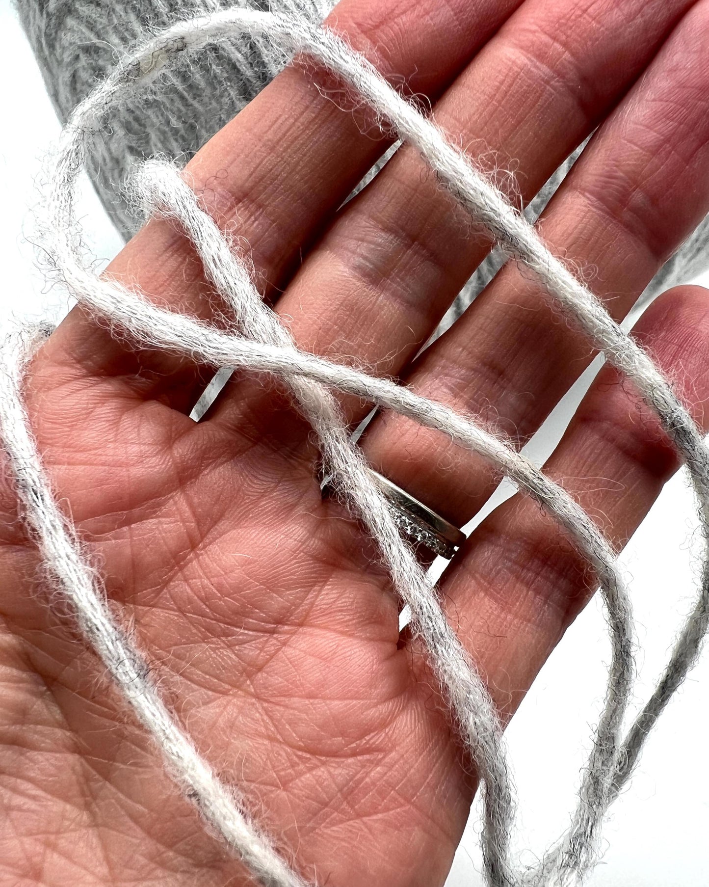 White yarn wrapped around a hand with a white background