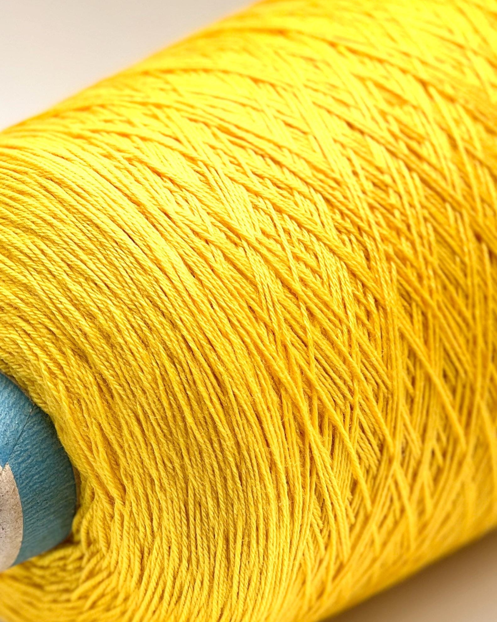 Close-up of a yellow spool of yarn on a light background