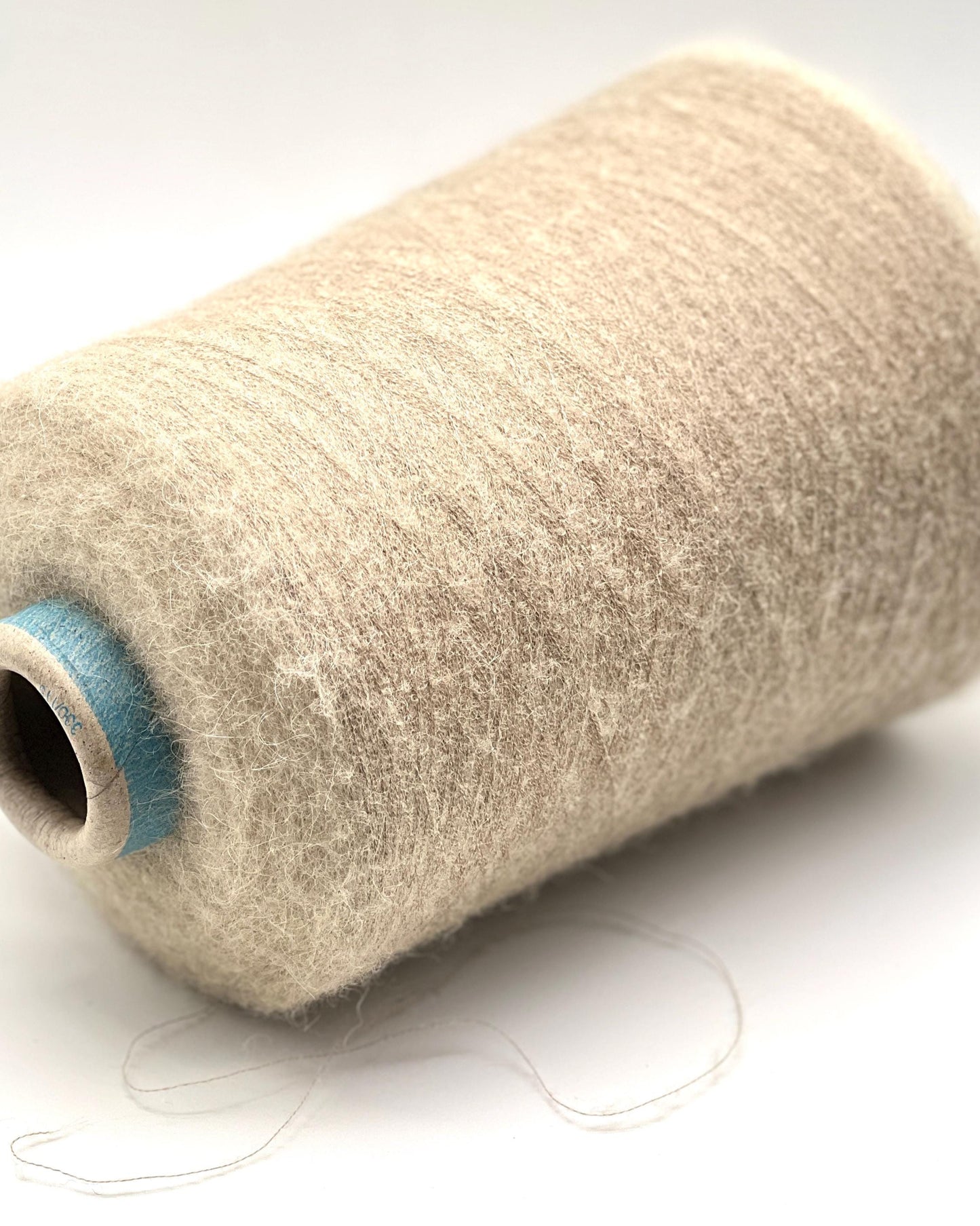 Spool of beige thread on a white background