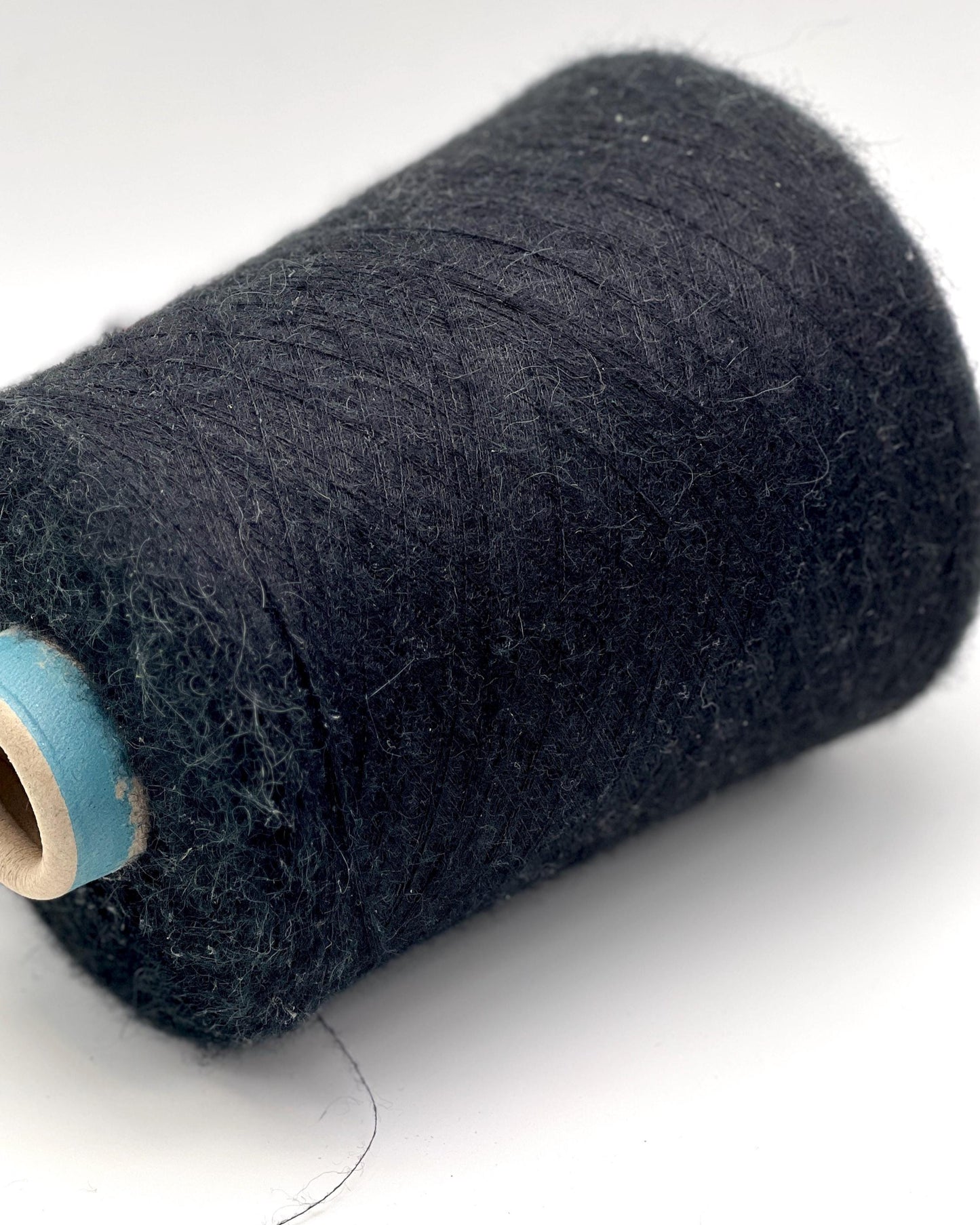 Spool of dark blue thread on a white background