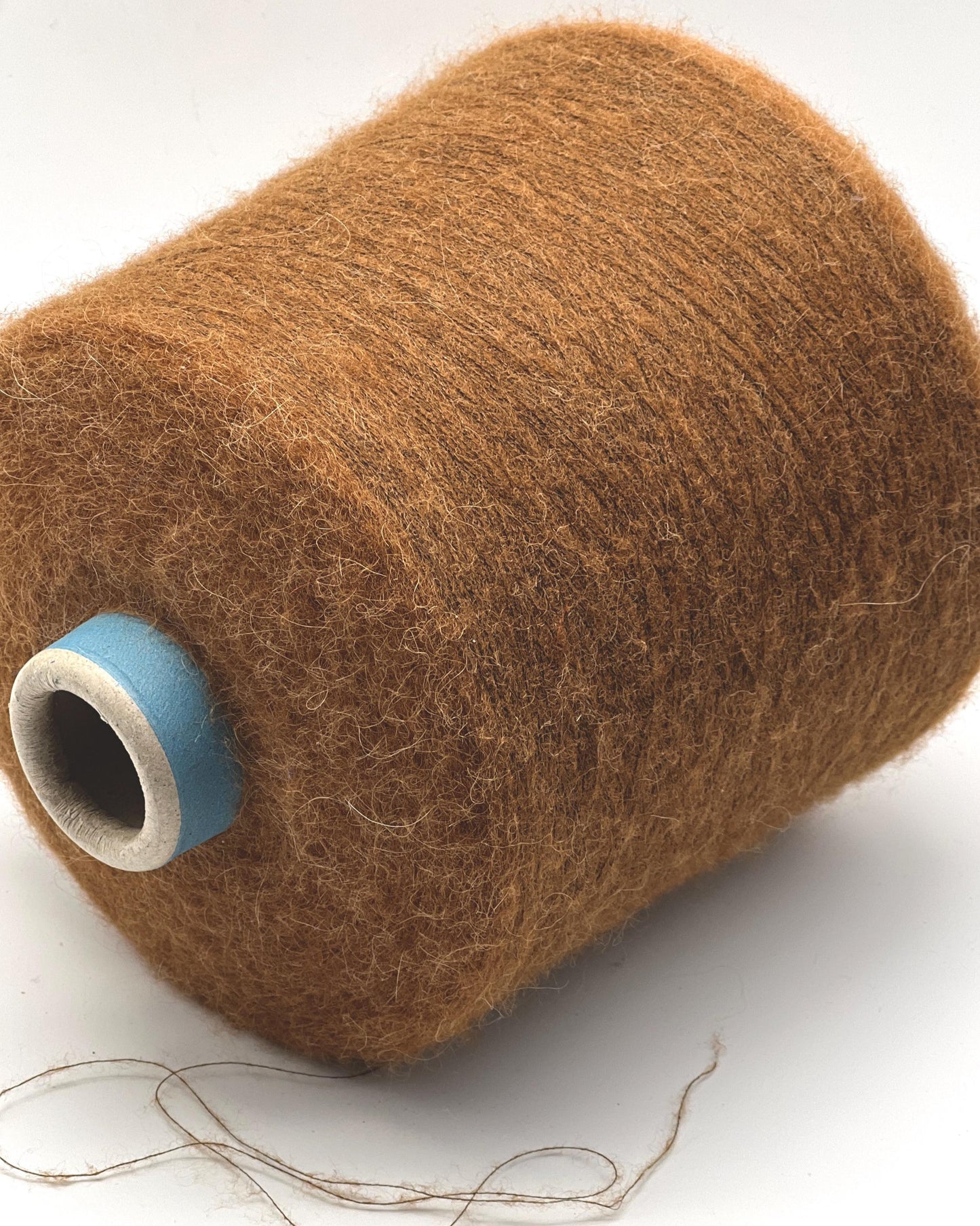 Brown spool of thread with a blue core on a white background
