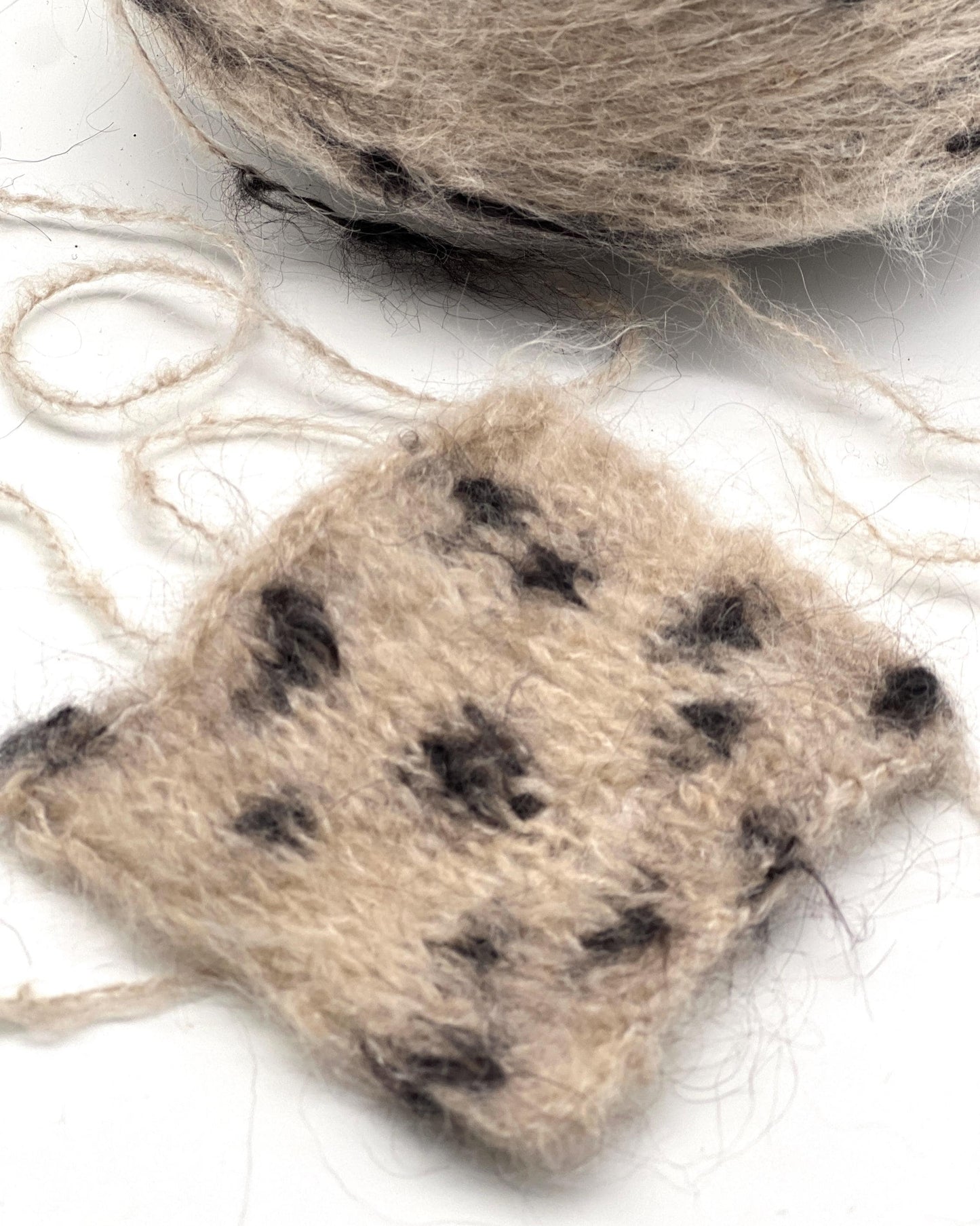 Knitted animal paw toy with spotted pattern on a white background