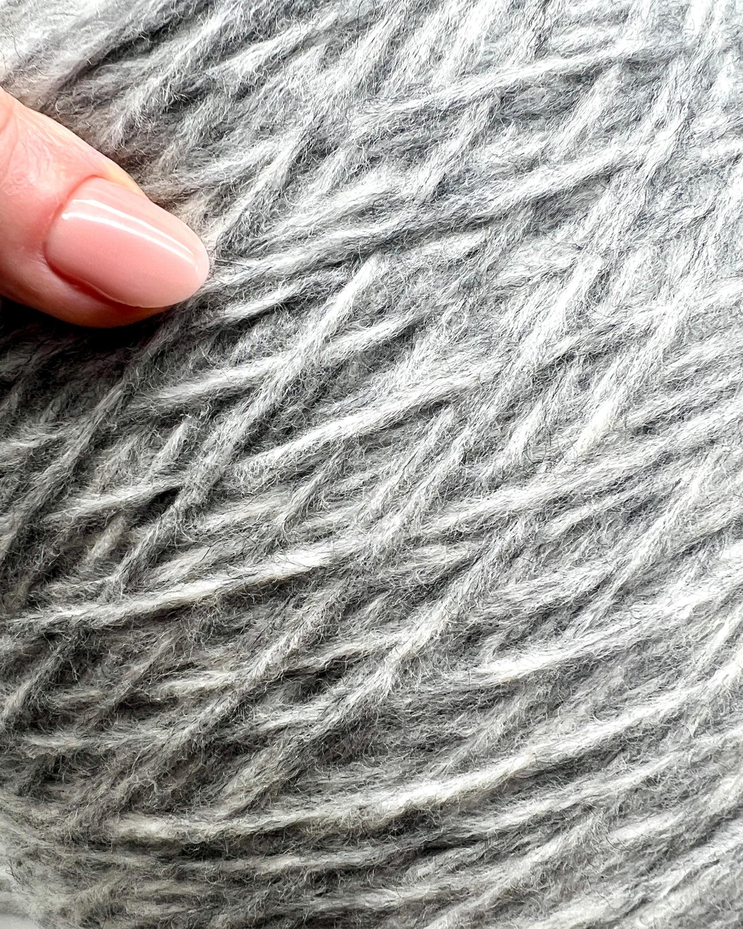 Close-up of gray yarn with a hand holding it