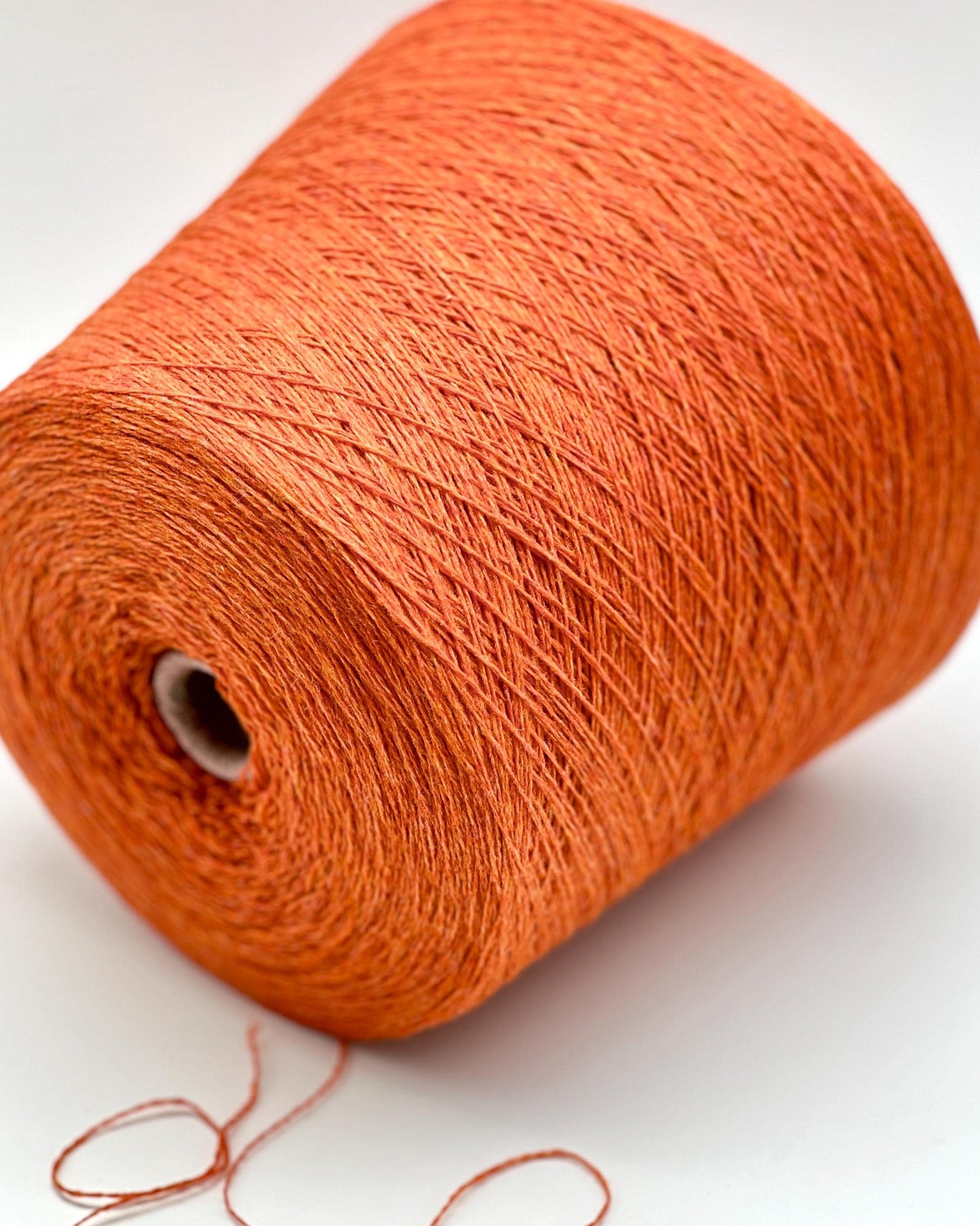 Spool of orange yarn on a white background