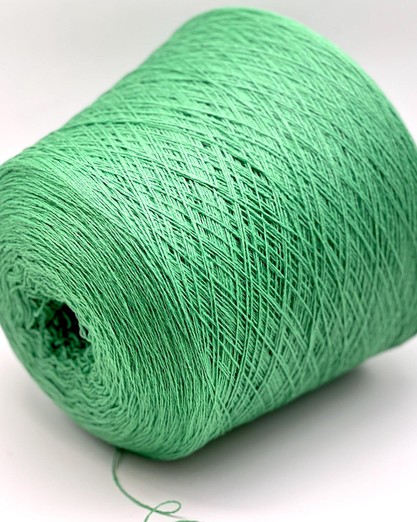 Green spool of yarn on a white background