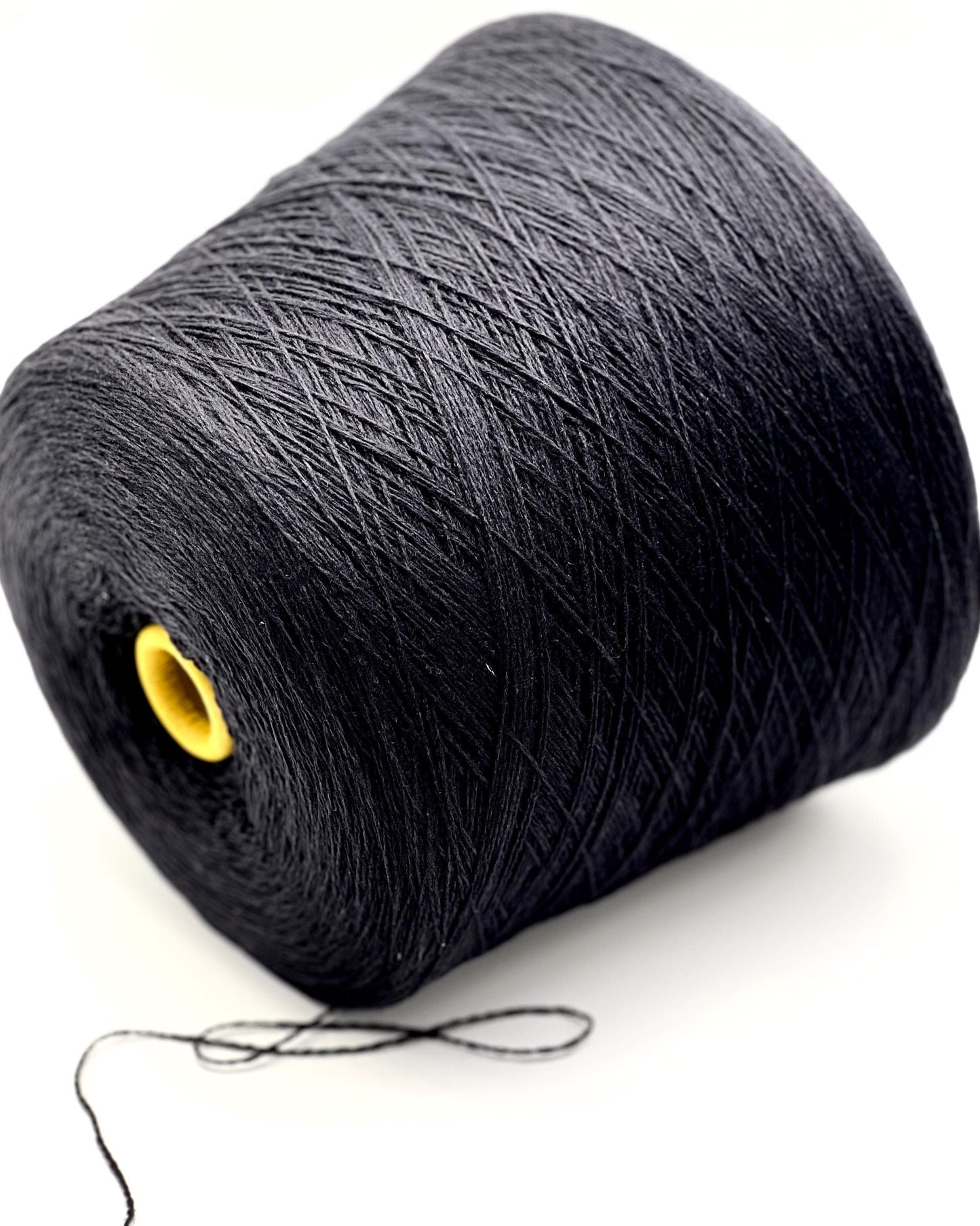 Large spool of black yarn with a yellow end on a white background