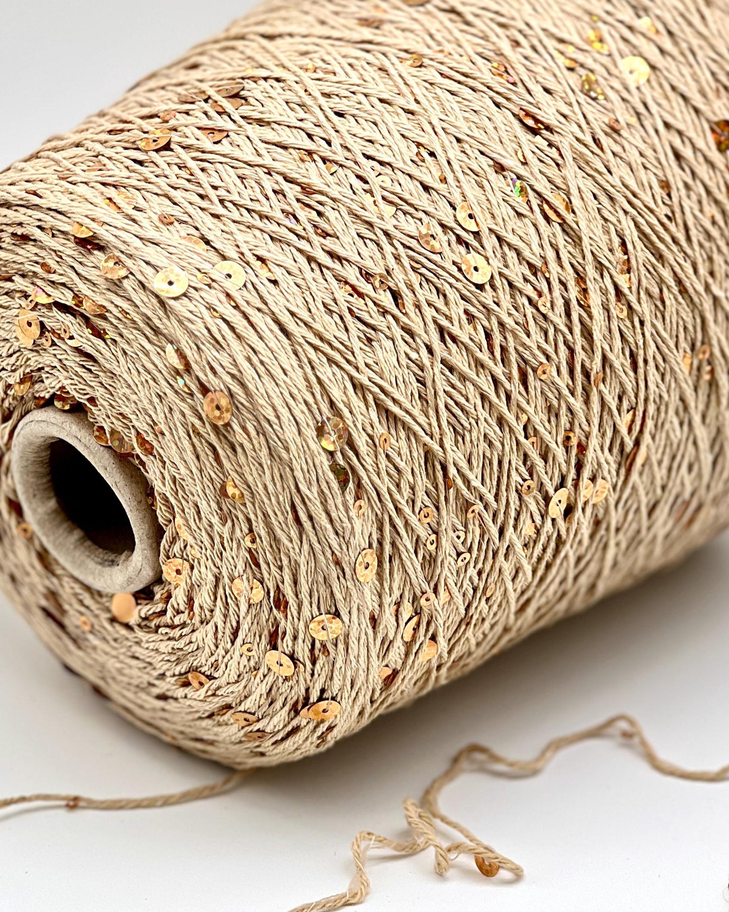 Close-up of a roll of beige string with small decorative elements on a white background