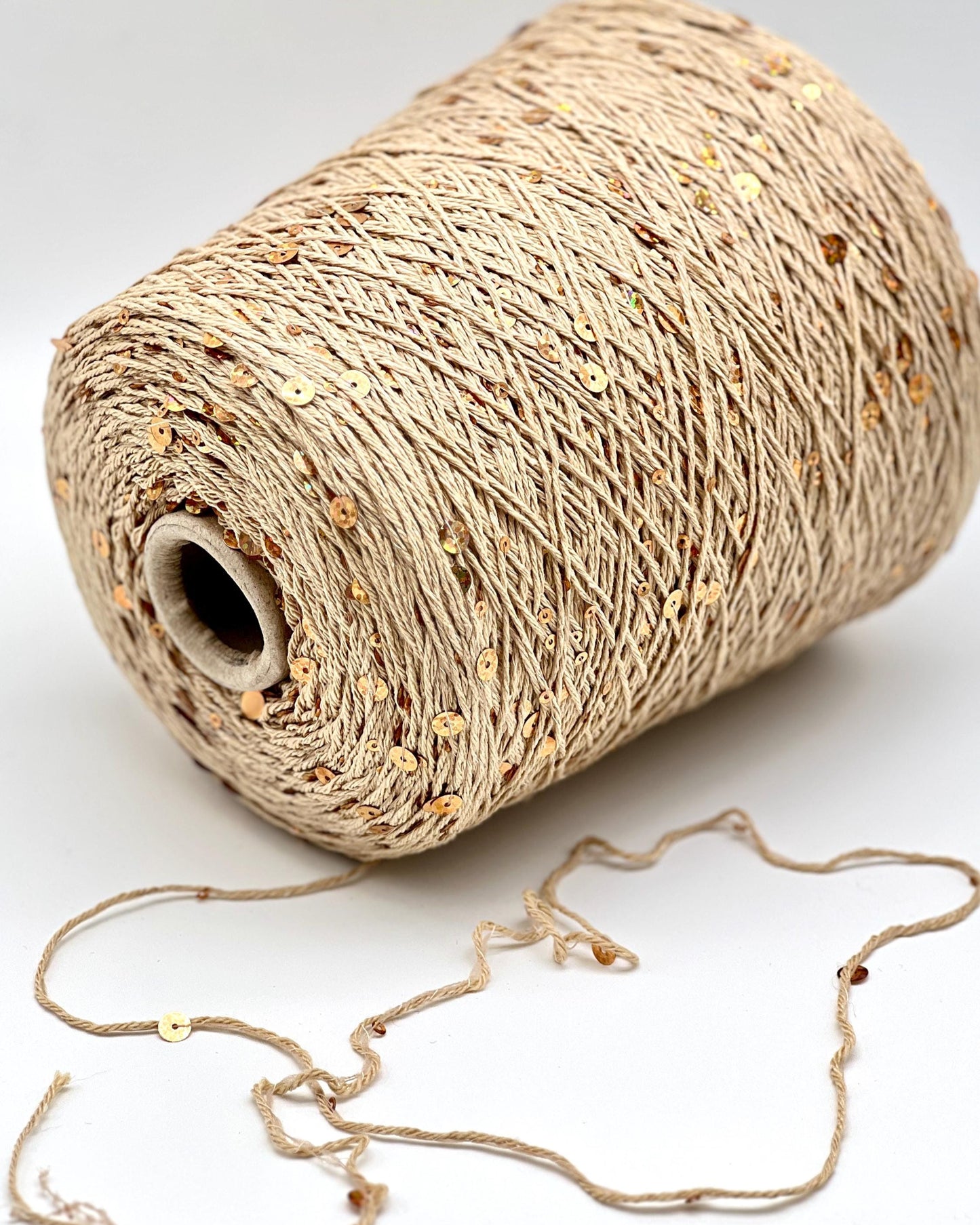 Spool of beige thread with a small piece unwound on a white background