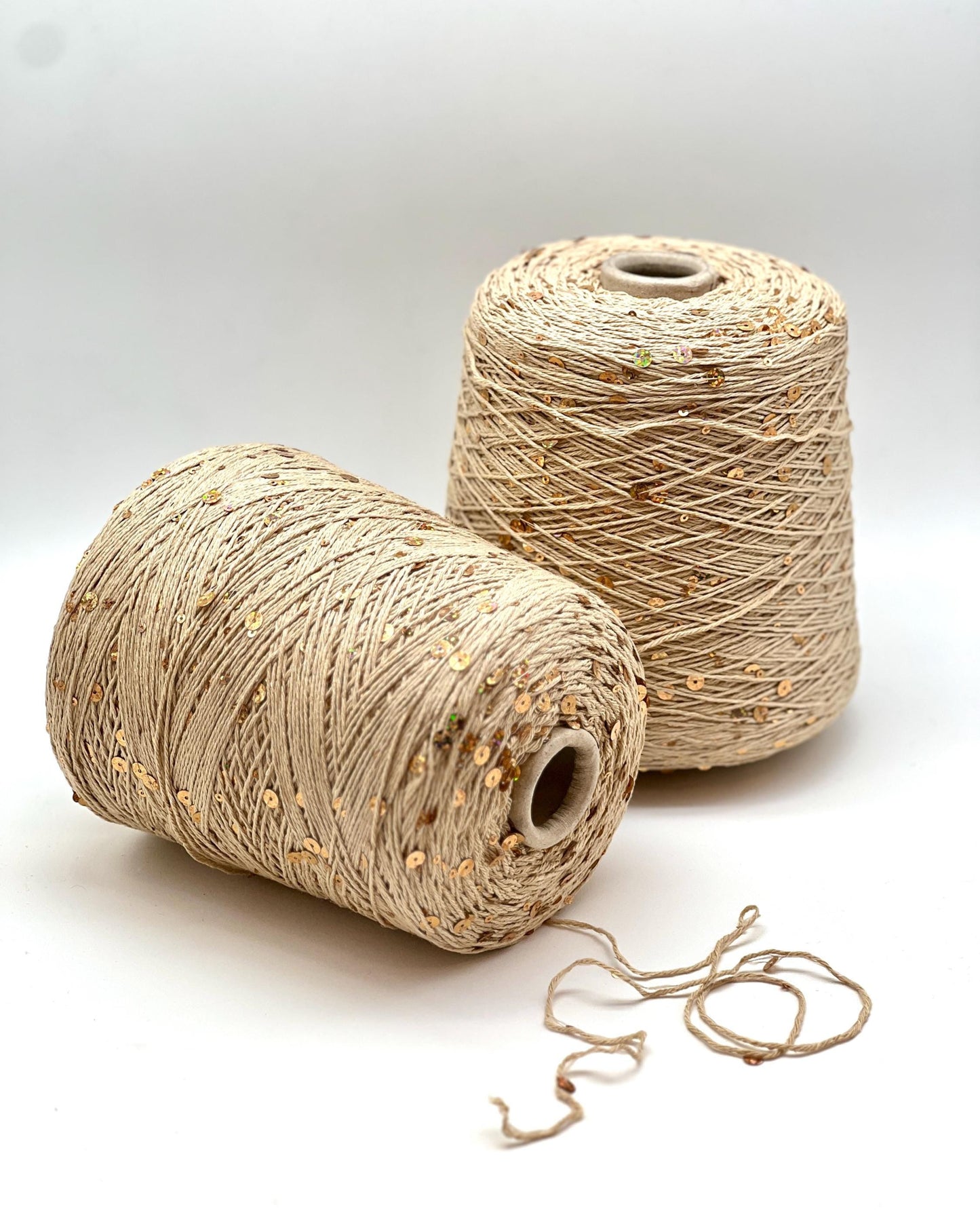 Two spools of beige thread on a white background