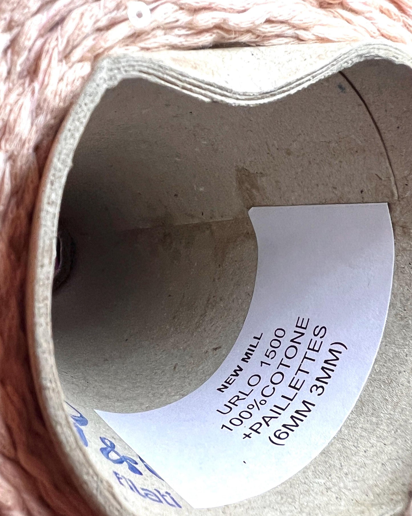 Close-up of a spool of thread with a label on a pink fabric background