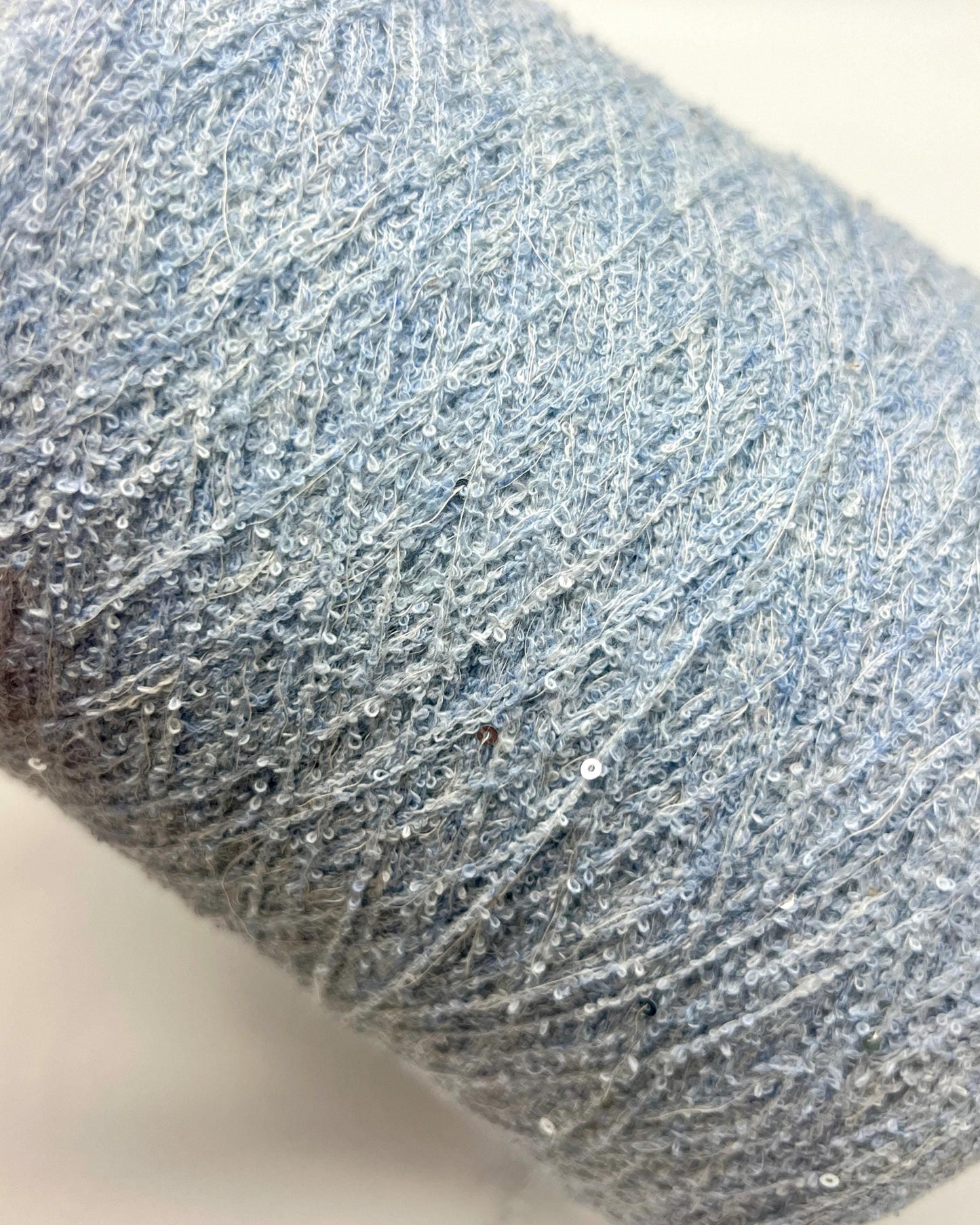 Close-up of a ball of blue yarn with glitter on a white background