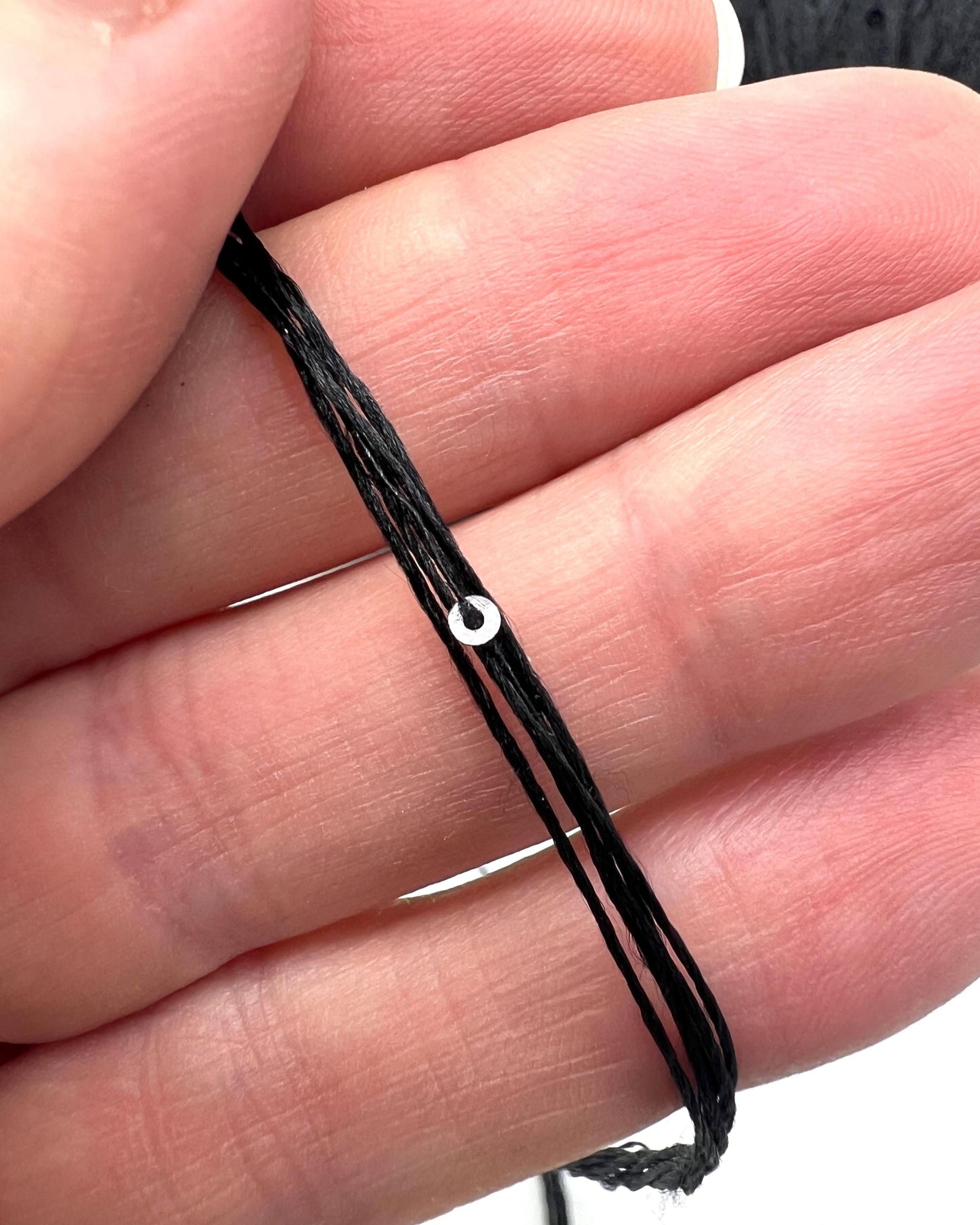 Black woven bracelet on a person's wrist with a close-up view.