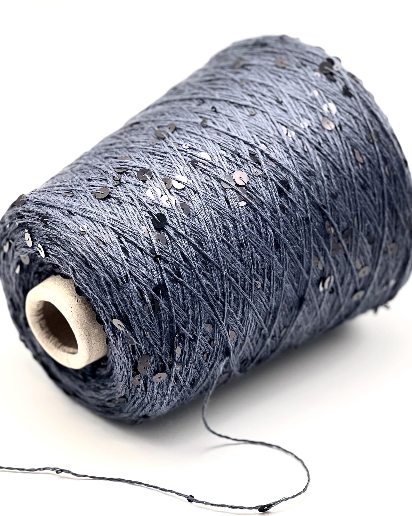 Spool of dark blue thread with sequins on a white background