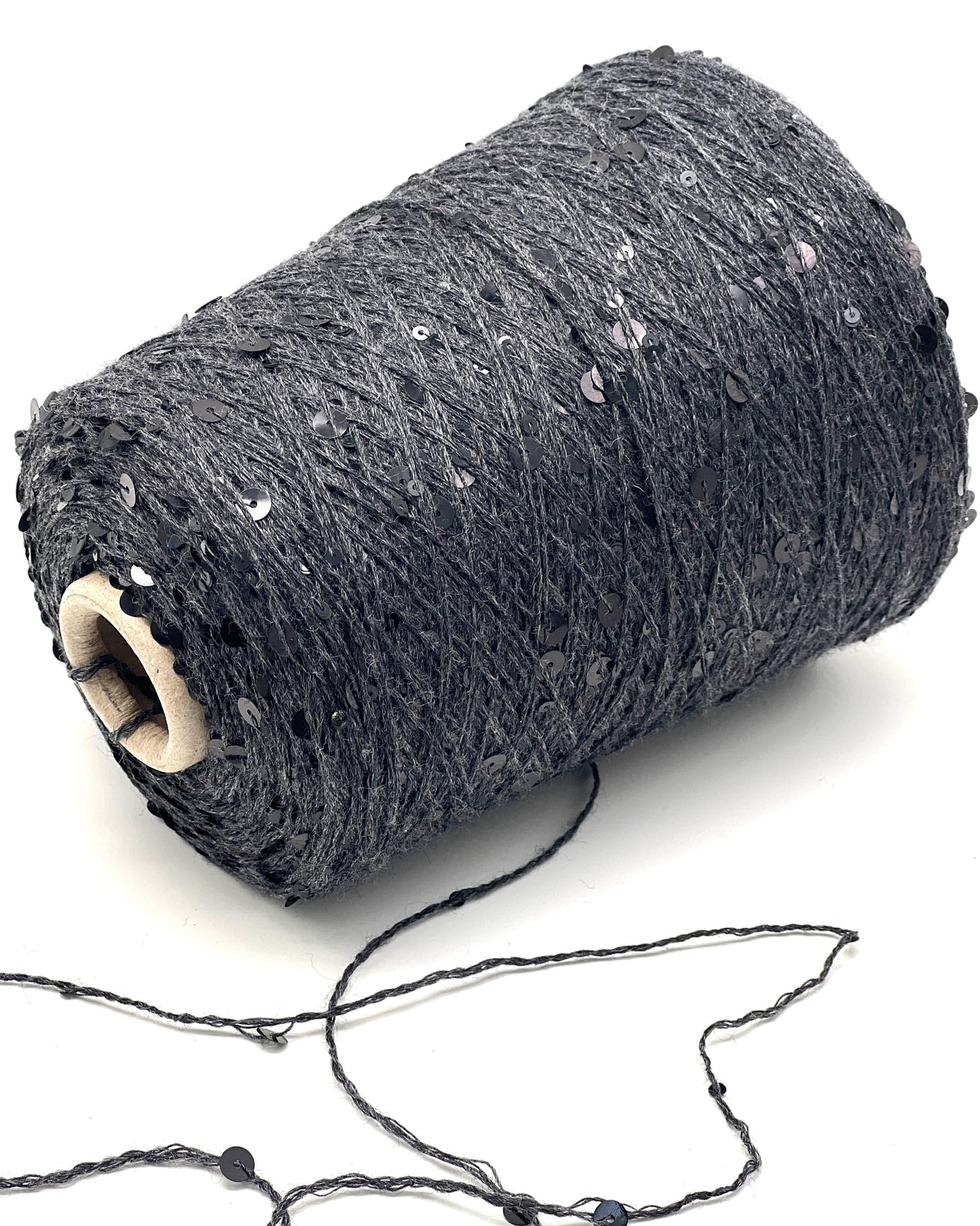 Roll of dark gray yarn with sequins on a white background