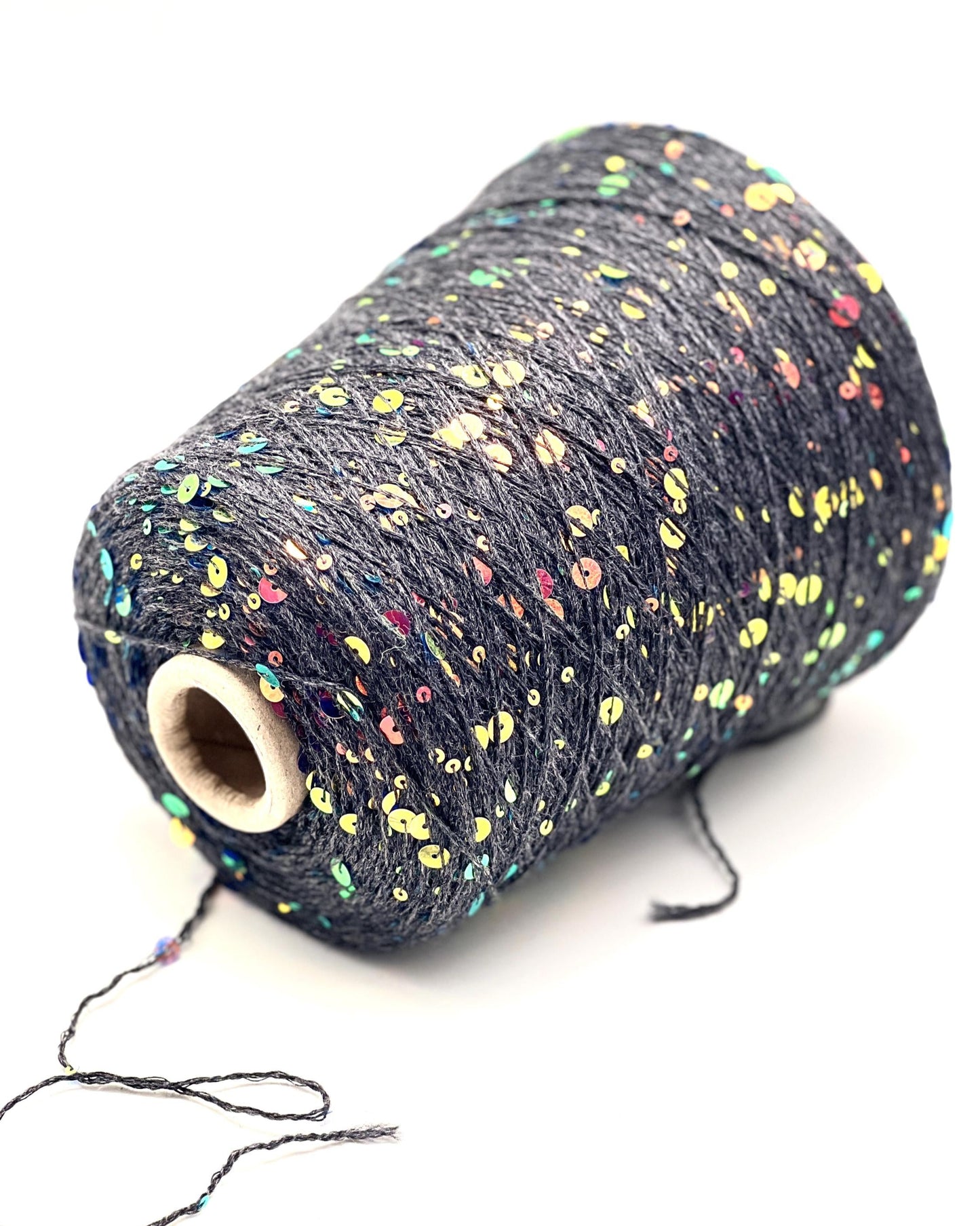 Spool of dark yarn with colorful speckles on a white background