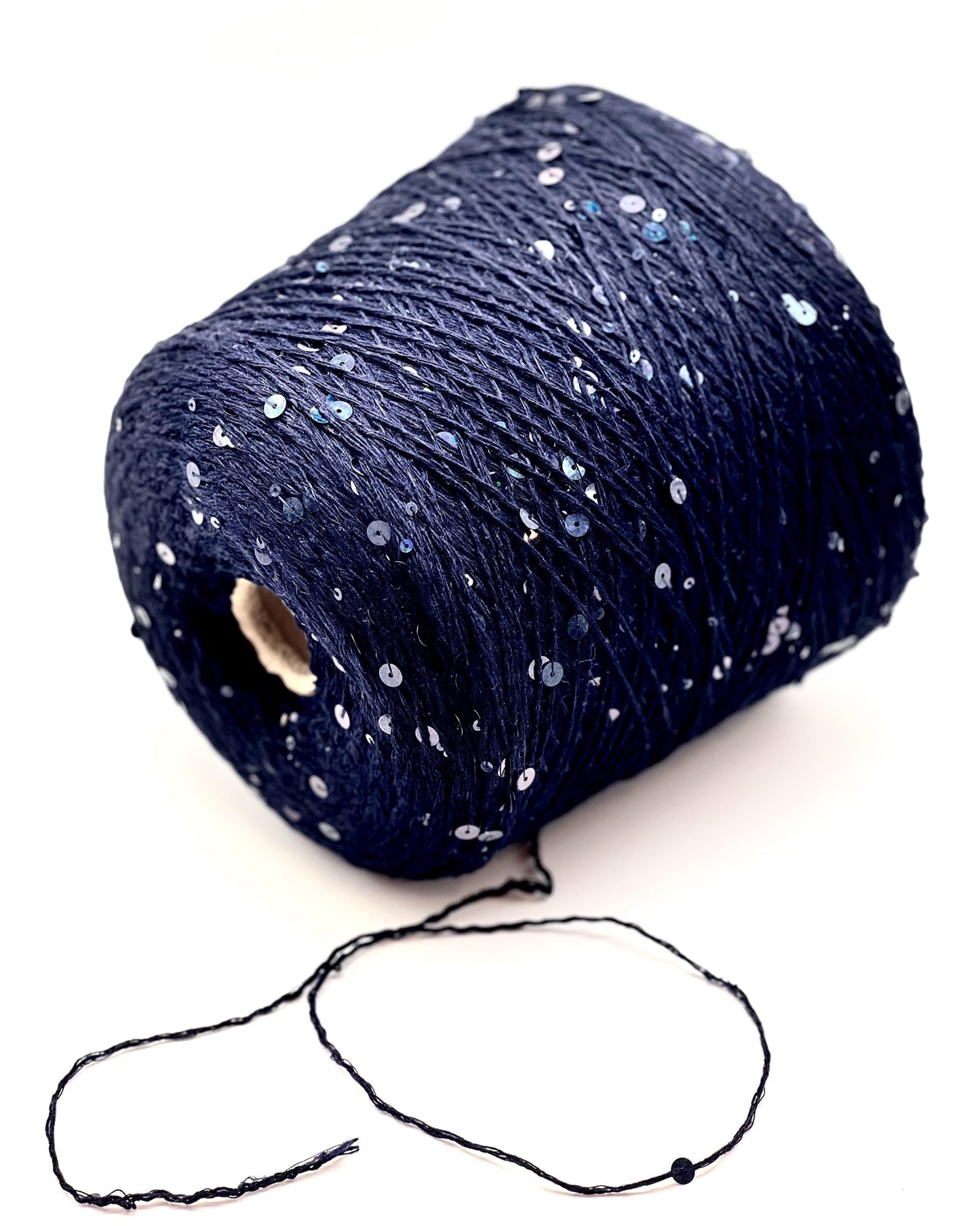 Spool of dark blue yarn with small white beads on a white background