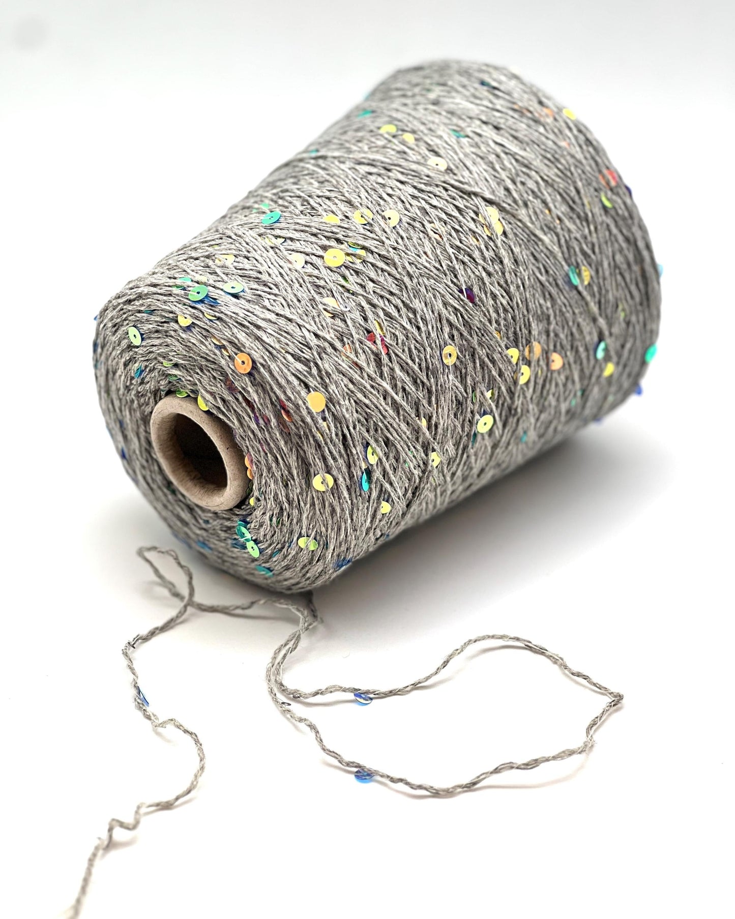 Spool of gray yarn with colorful specks on a white background