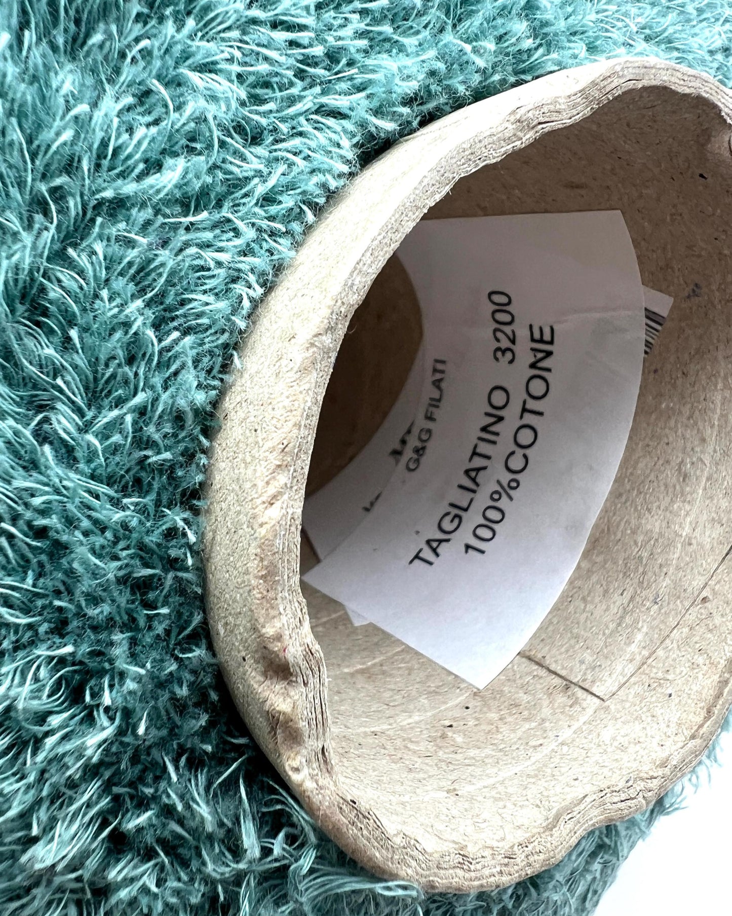 Cardboard tube with a label on a textured teal surface